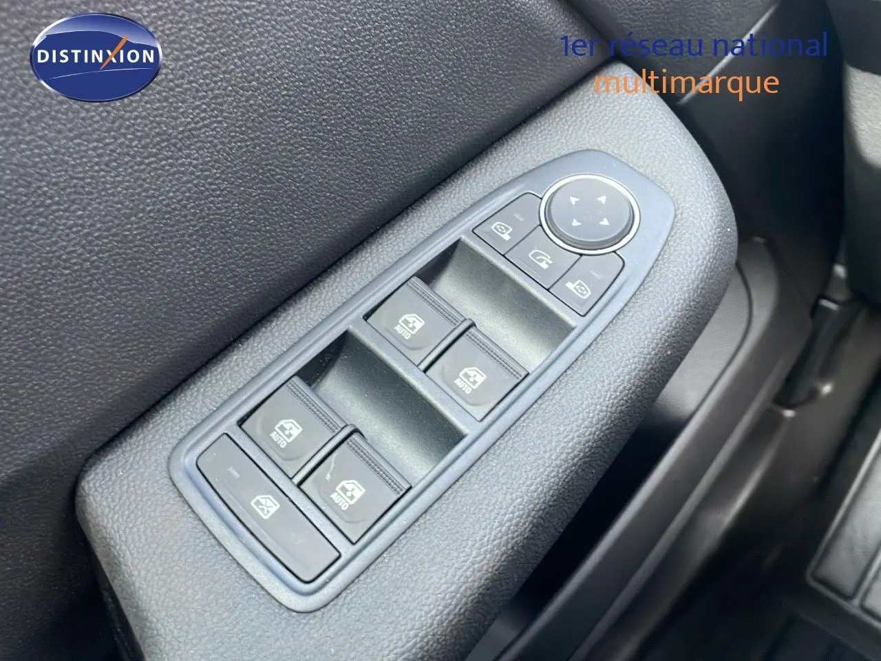 Gros plan sur les commandes des vitres électriques côté conducteur d'une Renault Clio noire étoile métal, version 2025.