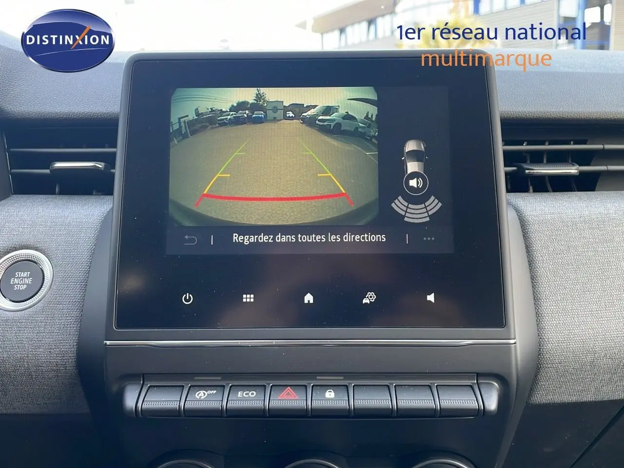 Écran central affichant la caméra de recul d'une Renault Clio noire étoile métal, tableau de bord moderne et boutons fonctionnels visibles.