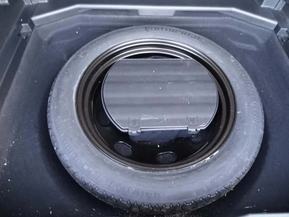 Gros plan sur la roue de secours galette dans le coffre du Peugeot 3008 gris Artense de 2017.