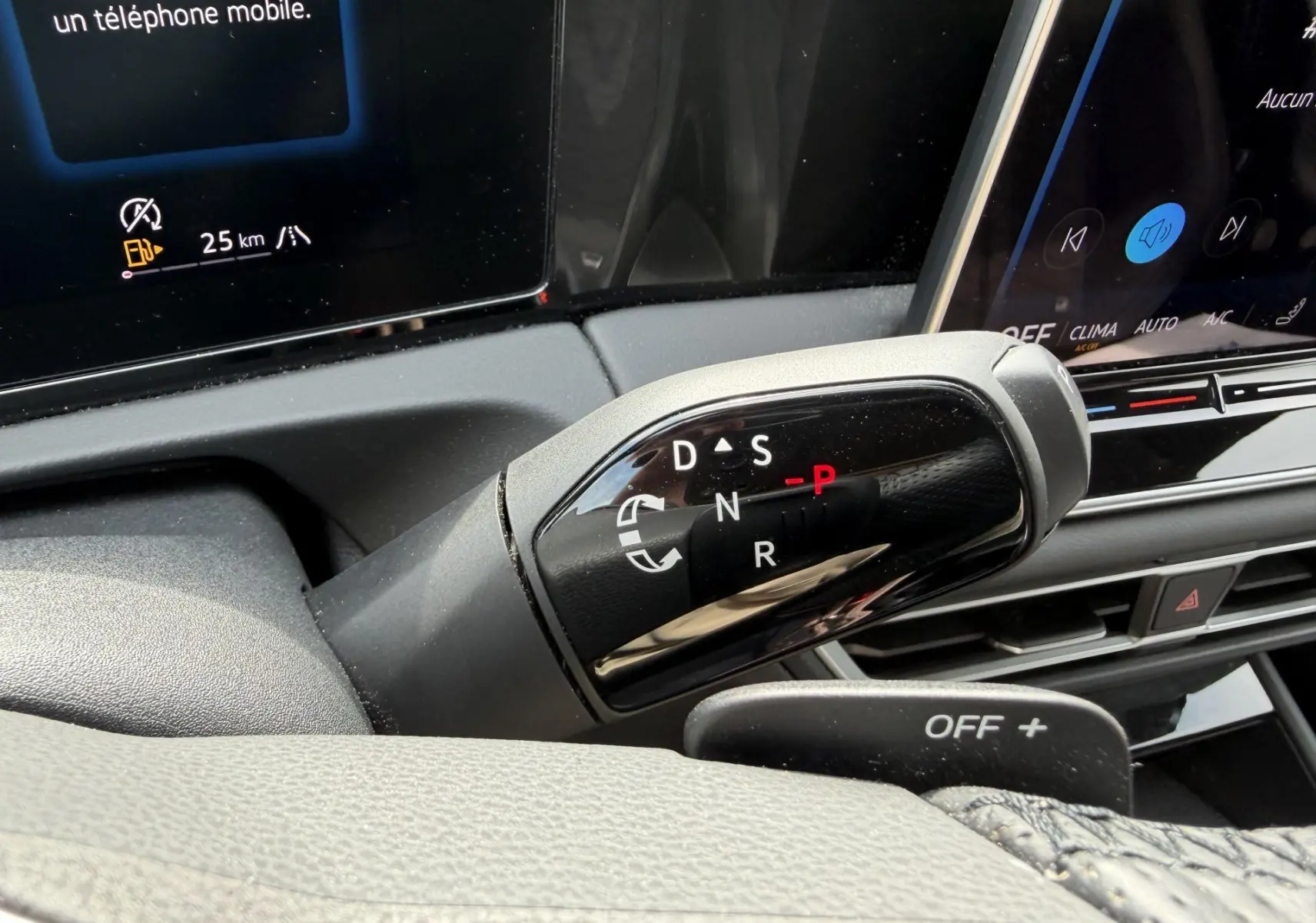 Gros plan sur le levier de vitesses DSG7 noir brillant du Volkswagen Tiguan 2025, avec écran tactile en arrière-plan.