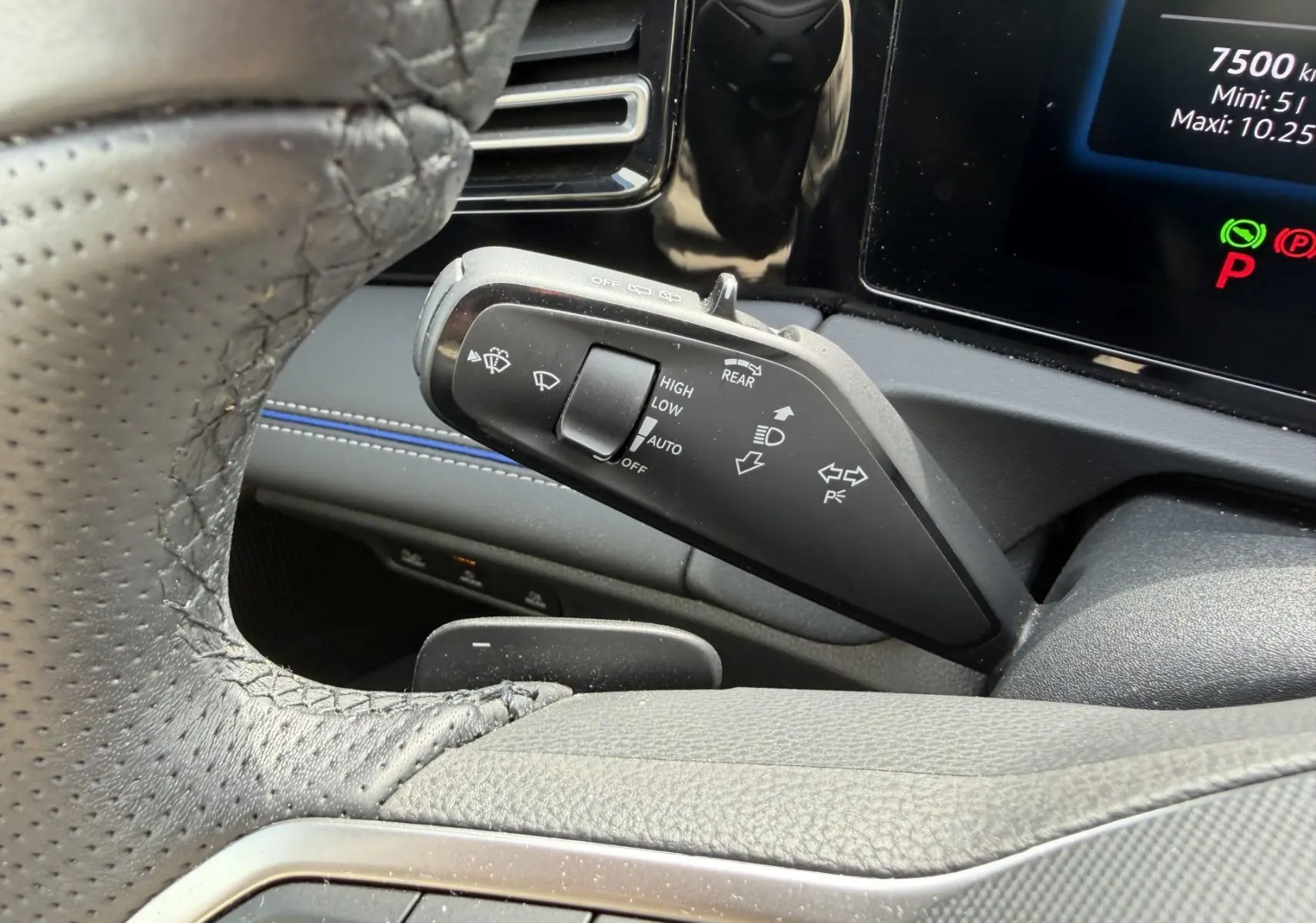 Gros plan sur la manette de commandes des essuie-glaces à gauche du volant noir perforé dans l’habitacle gris du Volkswagen Tiguan 2025.
