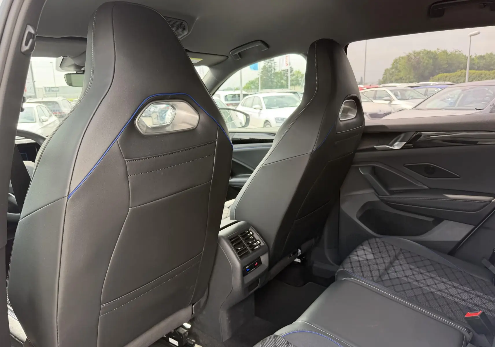 Vue arrière des sièges avant en cuir noir avec surpiqûres bleues et banquette arrière tissu gris à motifs dans un Volkswagen Tiguan gris.