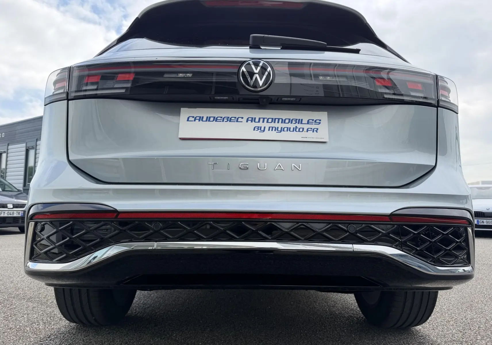 Vue arrière centrée du Volkswagen Tiguan gris métallisé 2025 avec feux LED et logo VW lumineux.