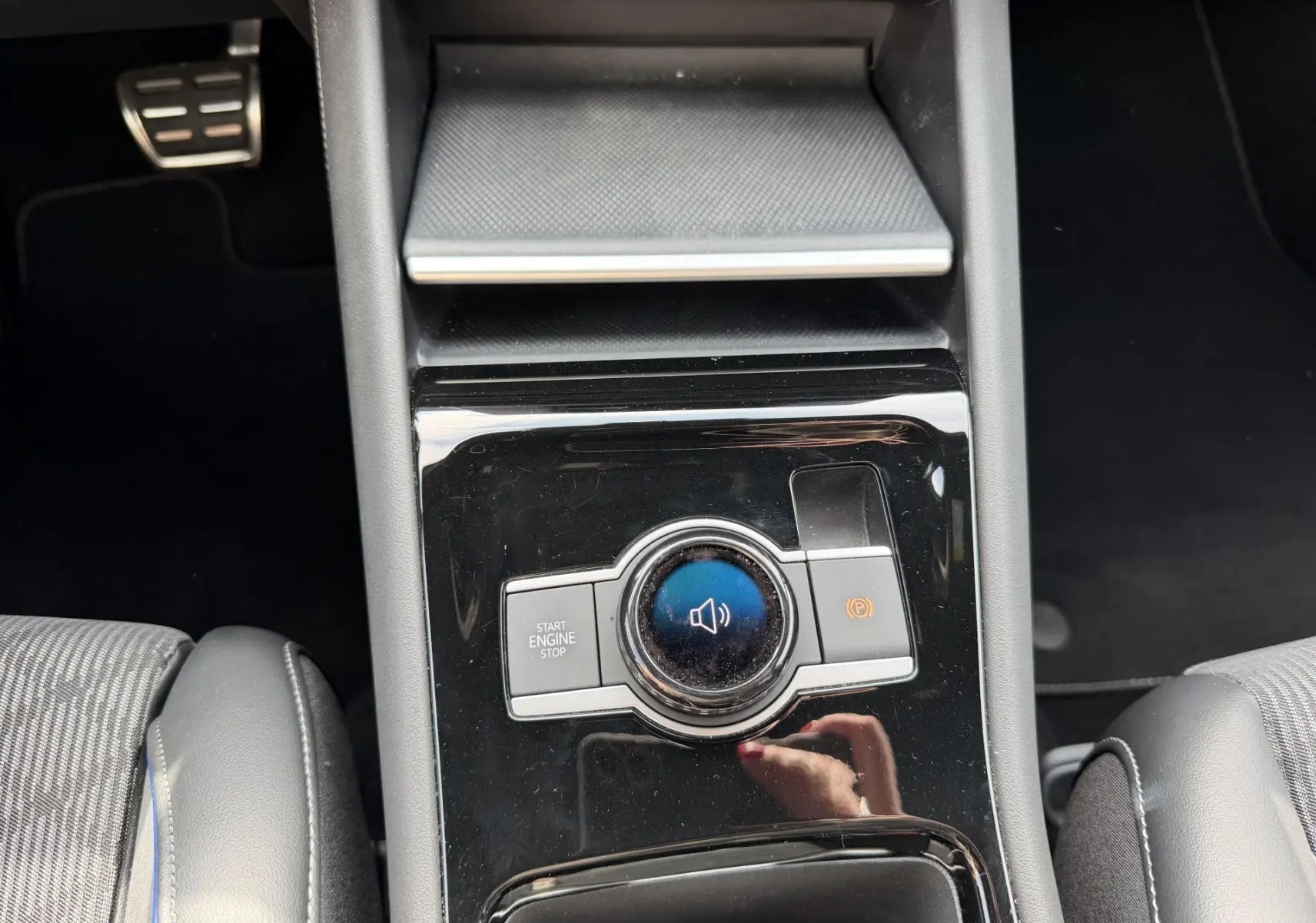 Gros plan sur la console centrale noire du Volkswagen Tiguan 2025 avec bouton Start/Stop et frein à main électronique.