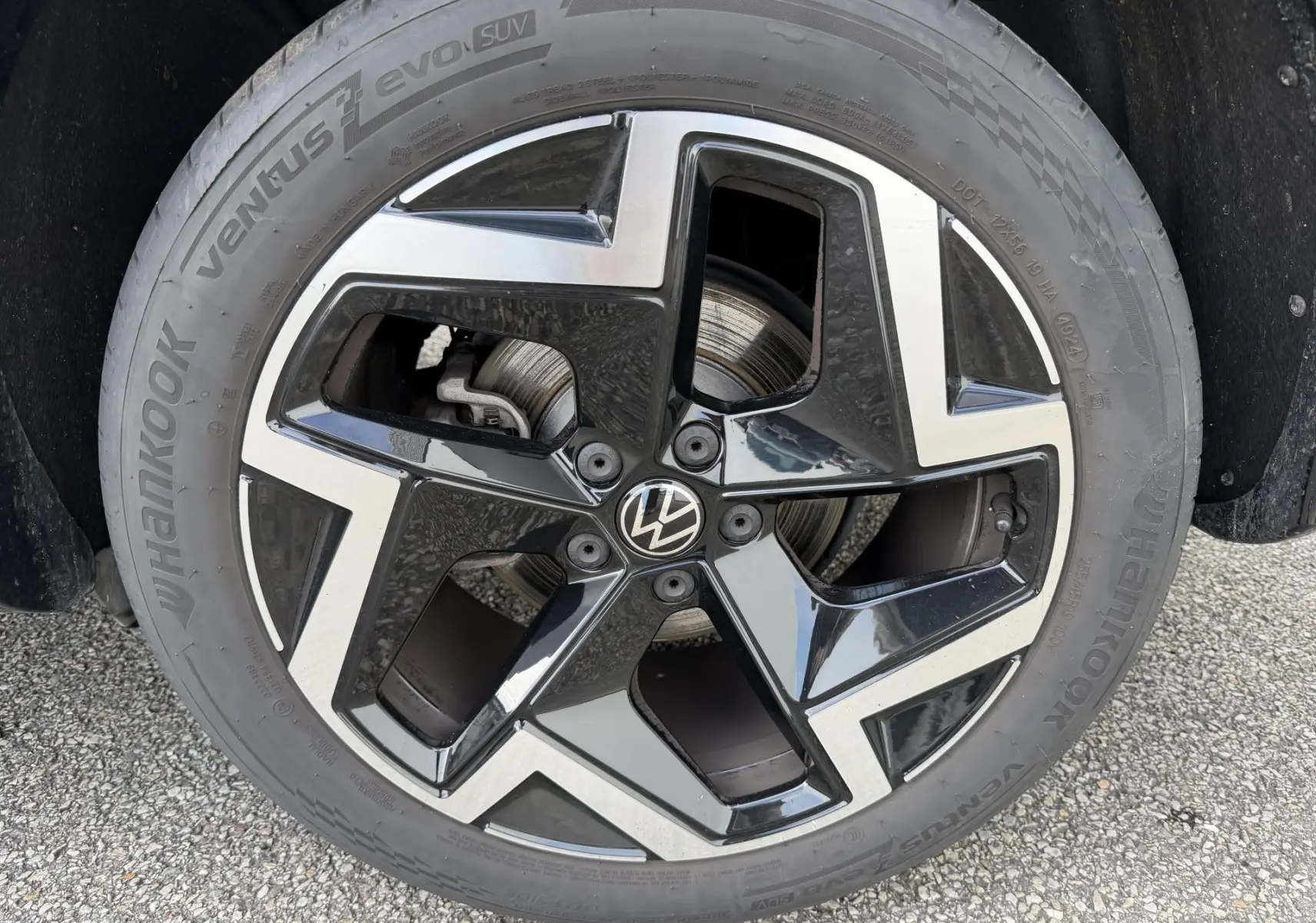 Gros plan sur la jante alliage 19 pouces bicolore du Volkswagen Tiguan gris, avec logo VW au centre.