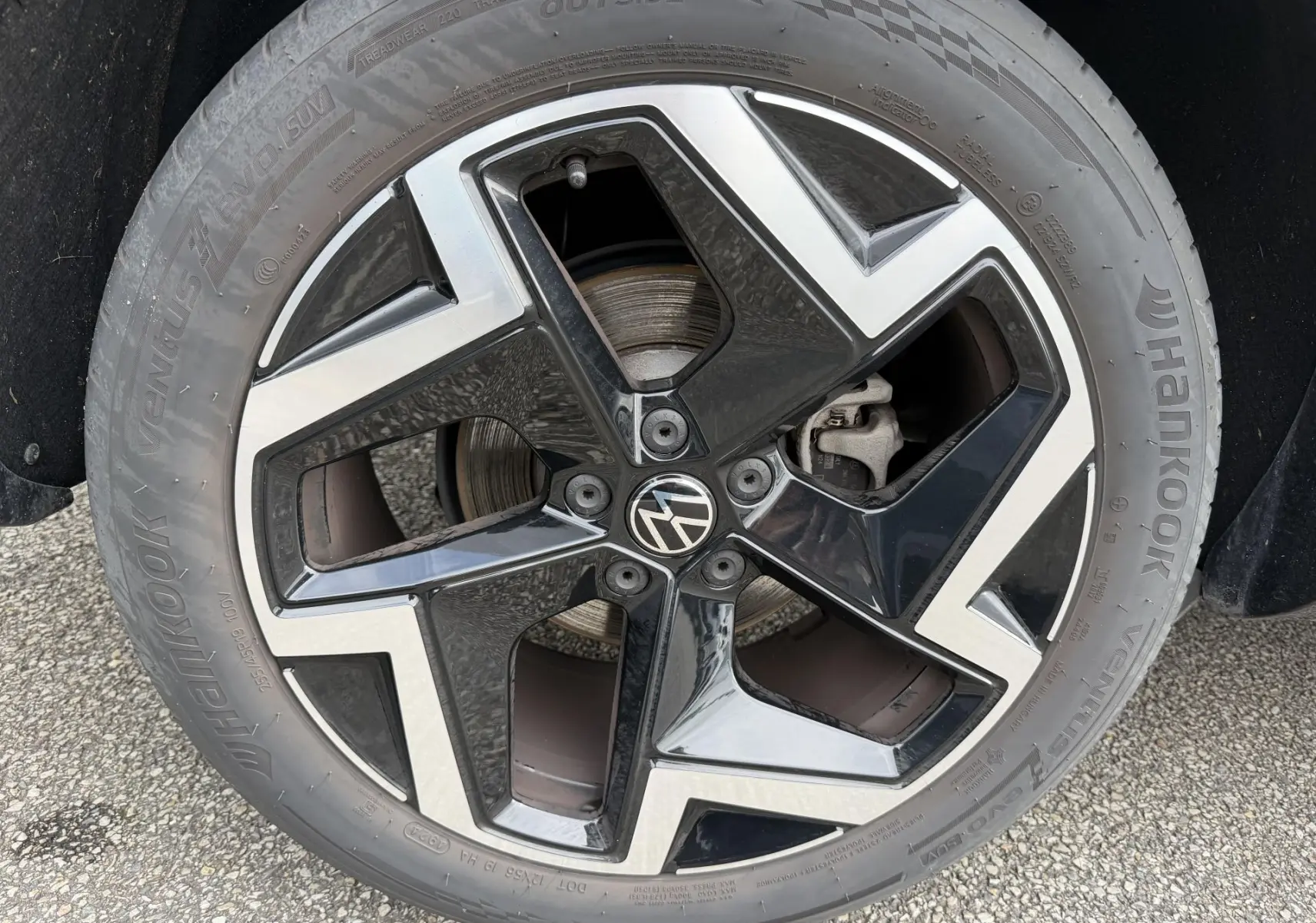 Gros plan sur la jante alliage 19 pouces bicolore noir et argent du Volkswagen Tiguan gris, avec logo VW central.