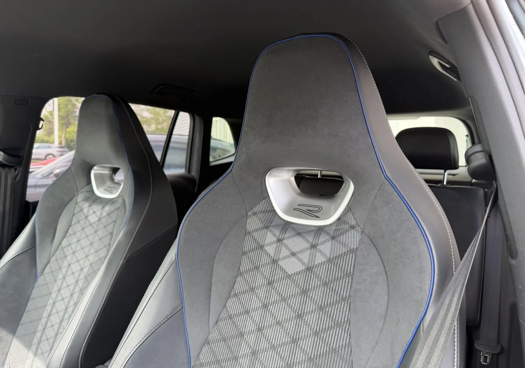 Gros plan sur les sièges avant sport gris avec surpiqûres bleues du Volkswagen Tiguan 2025, vue intérieure côté droit.