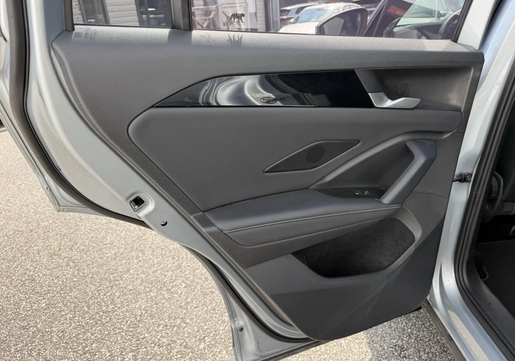 Vue rapprochée de la porte arrière gauche grise du Volkswagen Tiguan 2025 avec garniture noire et poignée intégrée.