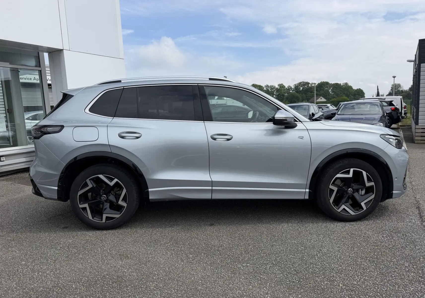 Vue de profil côté gauche d'un Volkswagen Tiguan gris métallisé avec jantes alliage 19 pouces et badge R-Line.