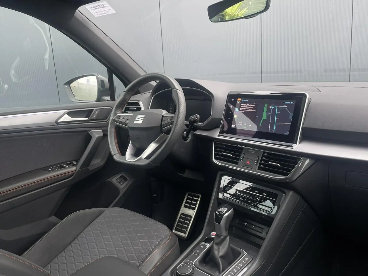 Intérieur côté conducteur du SEAT Tarraco 2024, volant cuir multifonction et écran tactile de navigation visible.