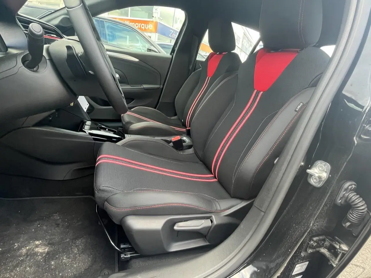 Vue intérieure côté conducteur de l'Opel Corsa GS Line 2022 noire avec sièges sport noirs et rouges.