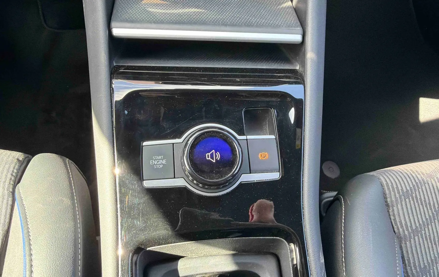 Vue plongeante sur la console centrale noire brillante du Volkswagen Tiguan 2025, avec bouton start/stop et frein à main électronique.