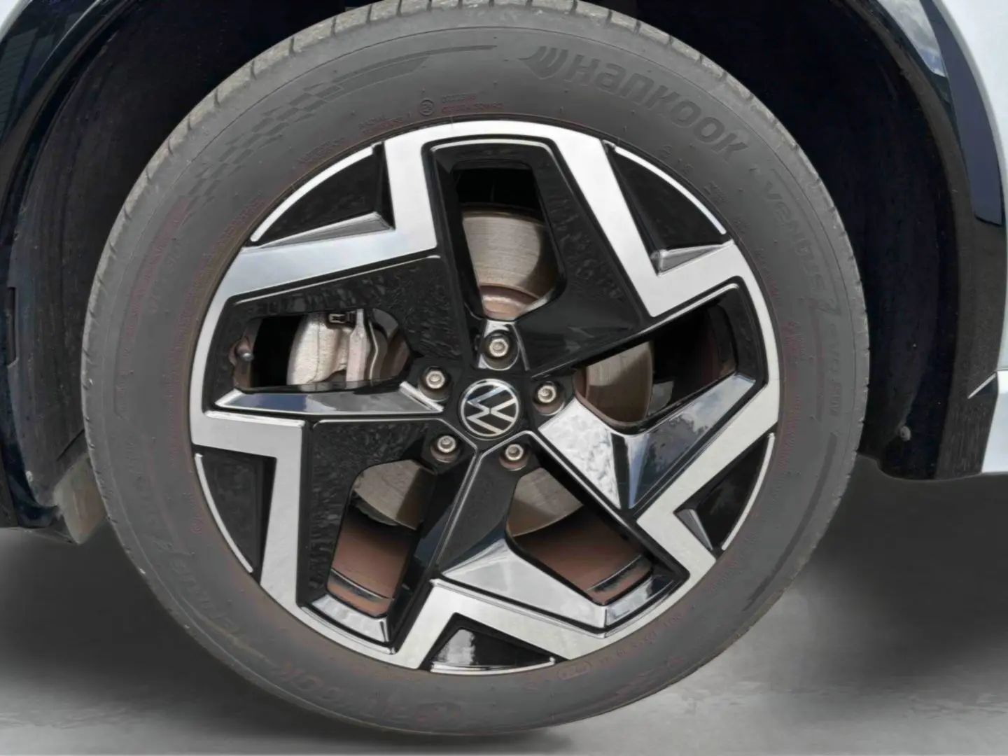 Gros plan sur la jante en alliage noir et argentée du Volkswagen Tiguan gris, mettant en valeur le logo VW central.