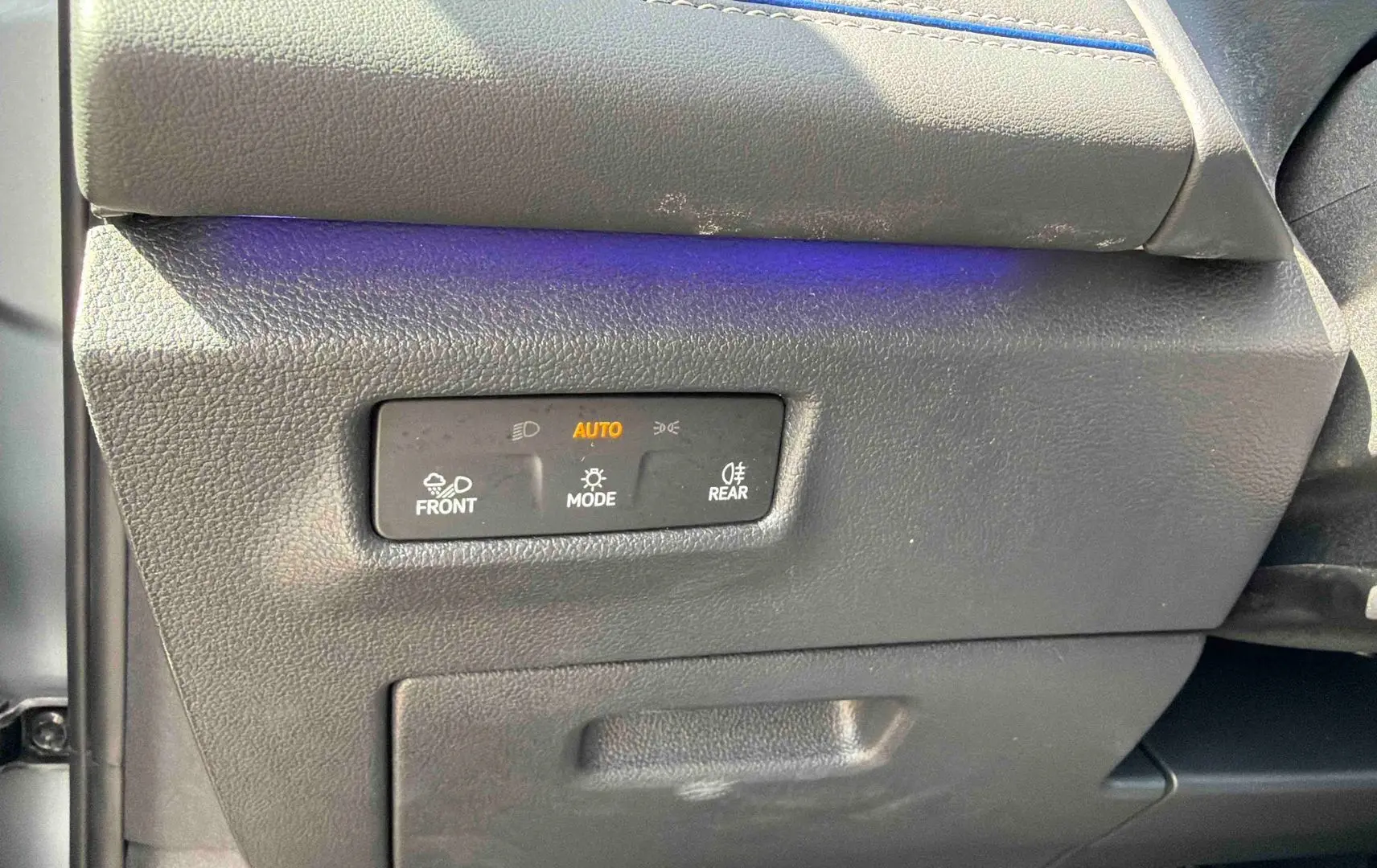 Détail des commandes d’éclairage sur le côté gauche du tableau de bord d’un Volkswagen Tiguan gris.