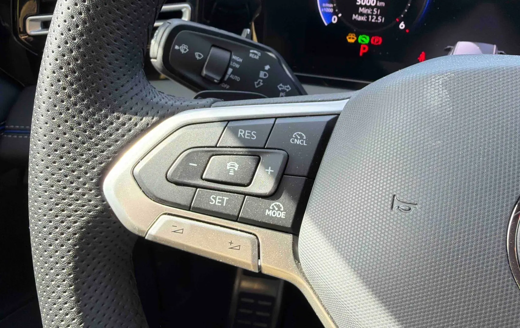 Gros plan sur le volant cuir perforé gris du Volkswagen Tiguan 2025 avec commandes du régulateur adaptatif.