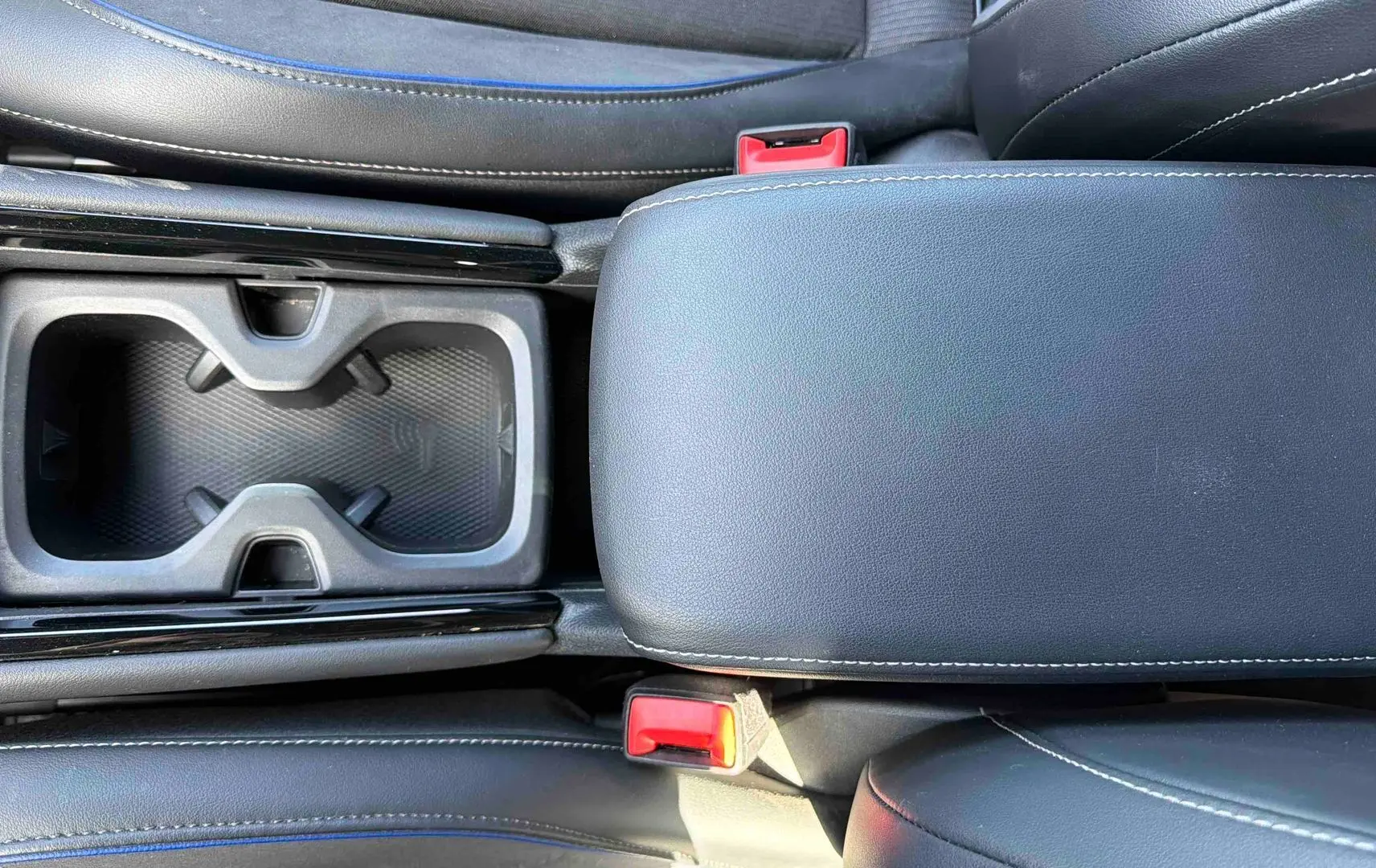 Vue plongeante sur la console centrale grise du Volkswagen Tiguan 2025 avec accoudoir et porte-gobelets noirs.