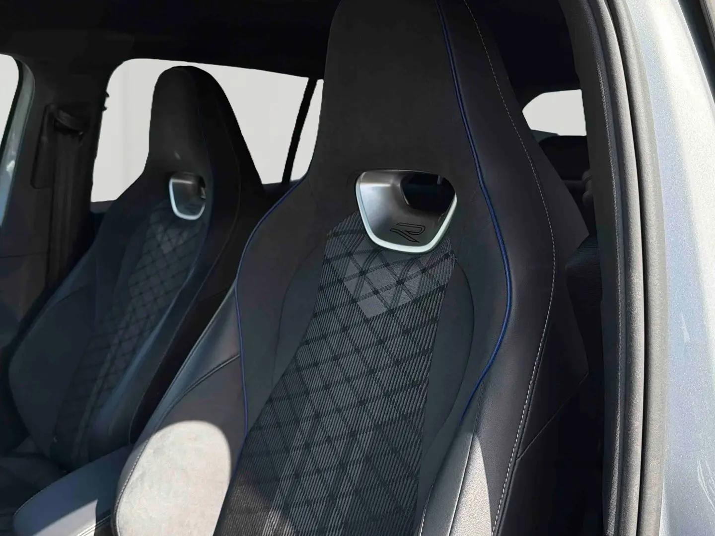Vue intérieure sur les sièges avant sport noirs avec surpiqûres bleues du Volkswagen Tiguan gris 2025.