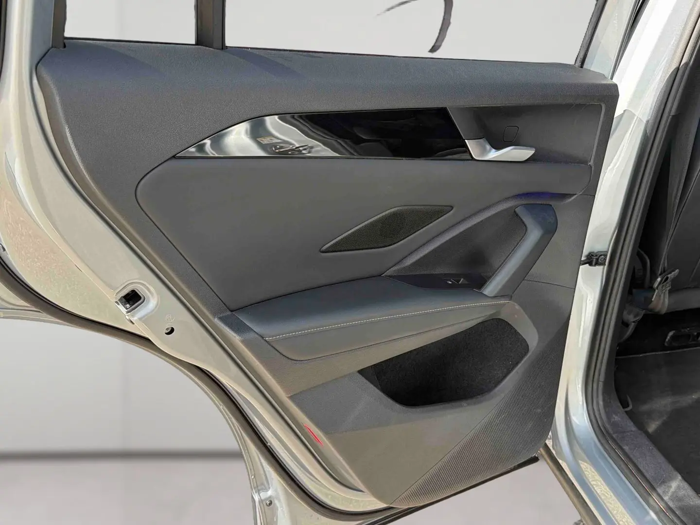 Vue rapprochée de la porte arrière droite grise du Volkswagen Tiguan 2025, avec garniture noire et poignée argentée.