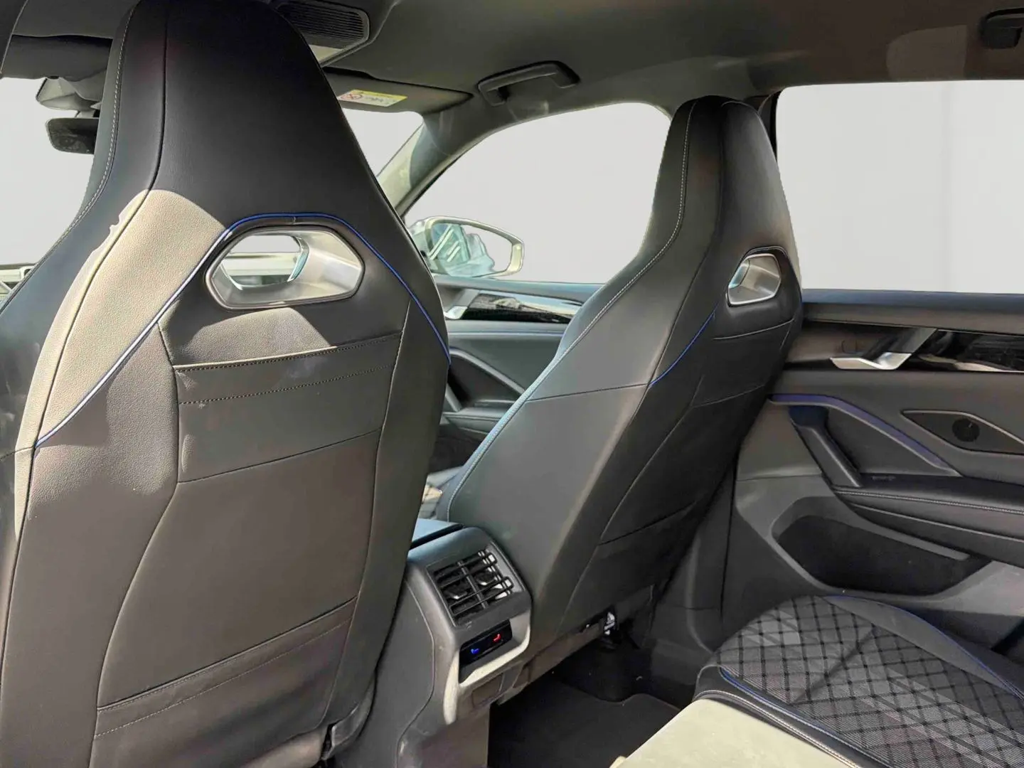 Vue arrière intérieure des sièges avant en cuir noir avec surpiqûres bleues du Volkswagen Tiguan 2025.