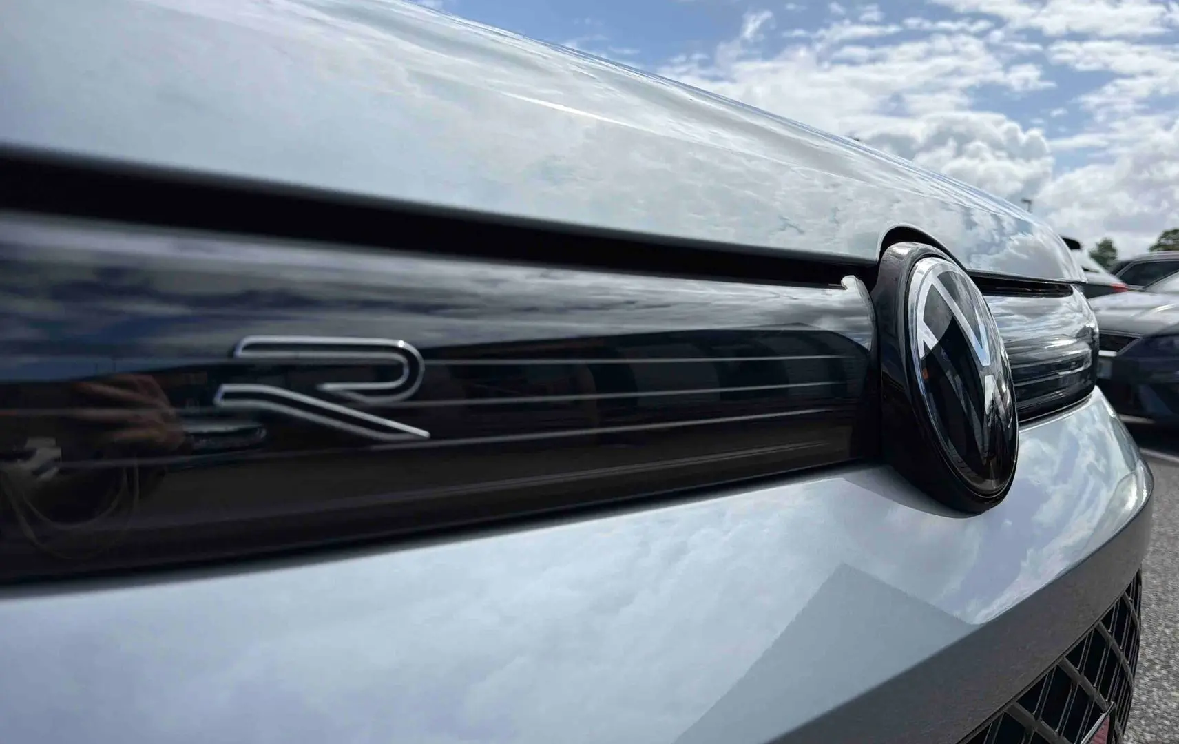 Gros plan sur la calandre avant grise du Volkswagen Tiguan 2025 avec logo VW et sigle R noir brillant.