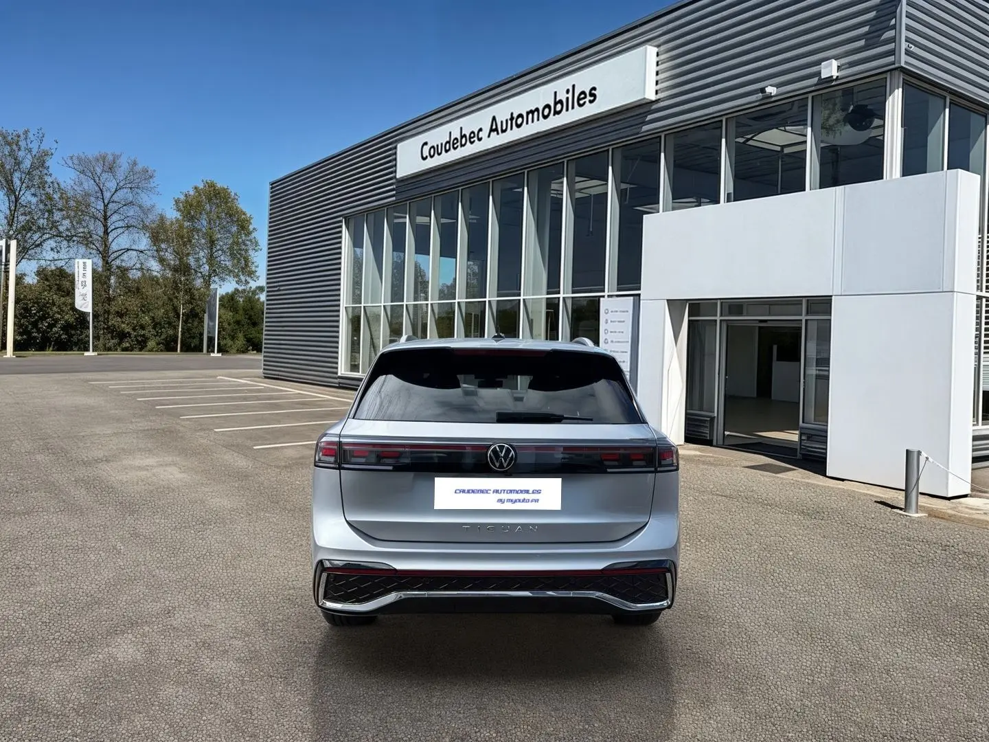 Vue arrière d’un Volkswagen Tiguan gris 2025 garé devant un concessionnaire Coudebec Automobiles.