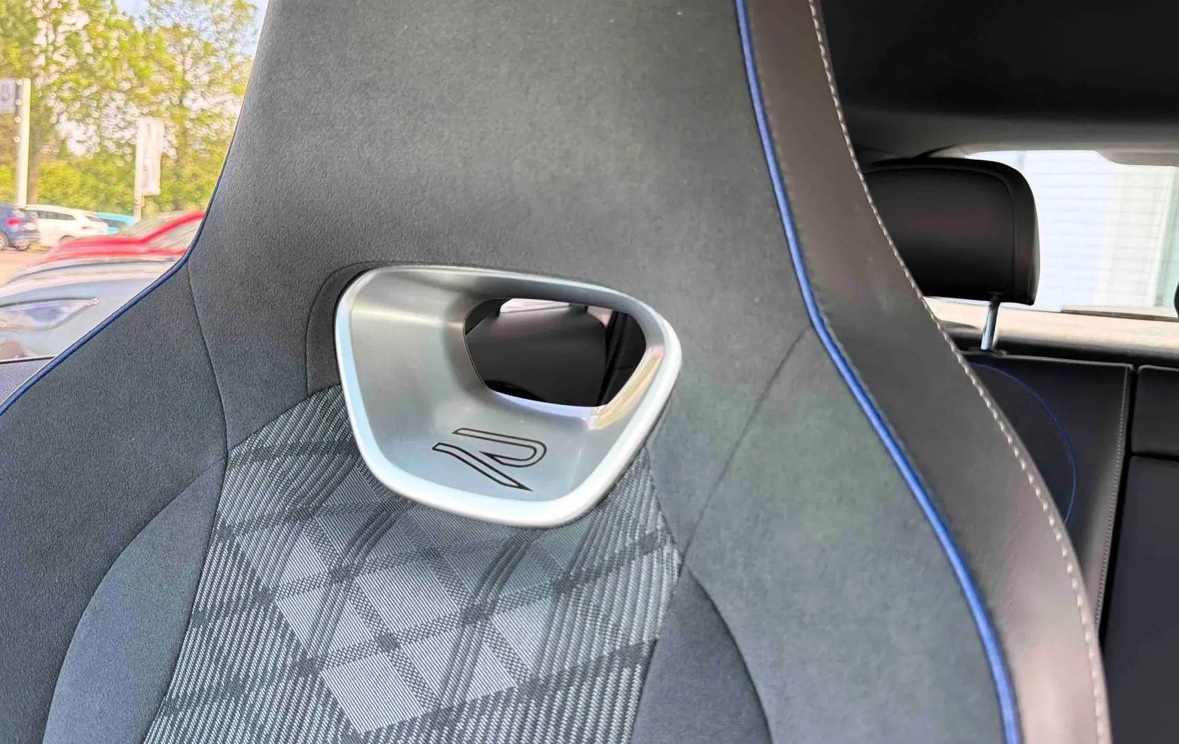 Détail du siège avant gris avec surpiqûres bleues et logo R, intérieur du Volkswagen Tiguan 2025.