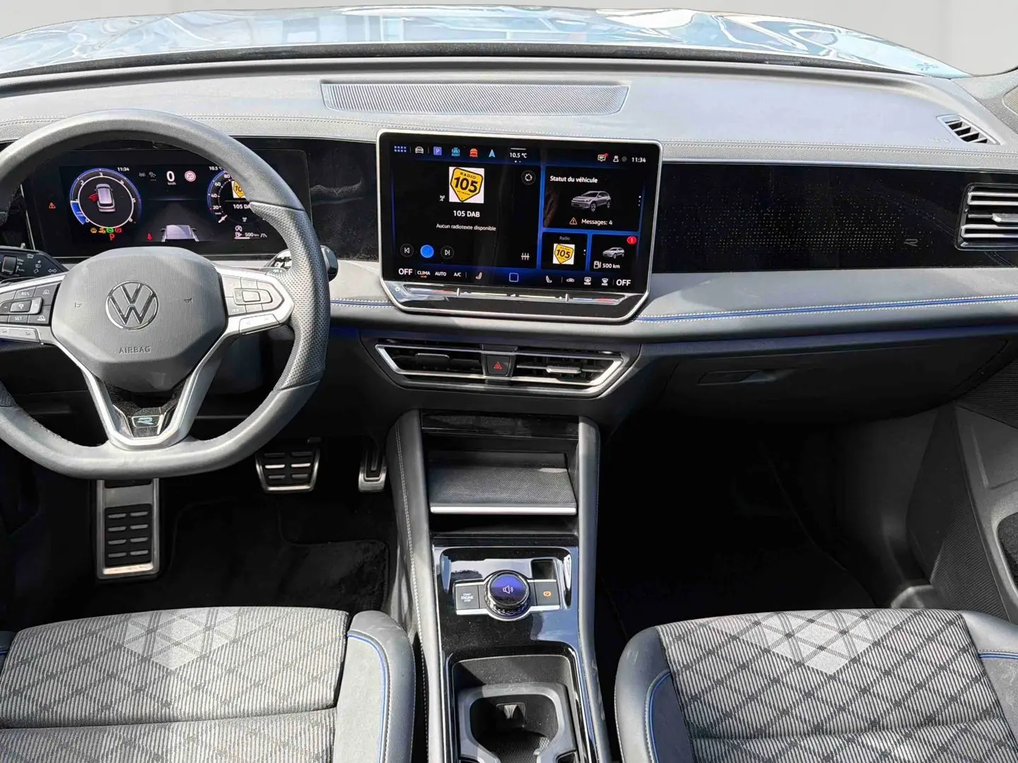 Vue intérieure avant du Volkswagen Tiguan 2025, tableau de bord noir avec écran tactile central et volant multifonction.