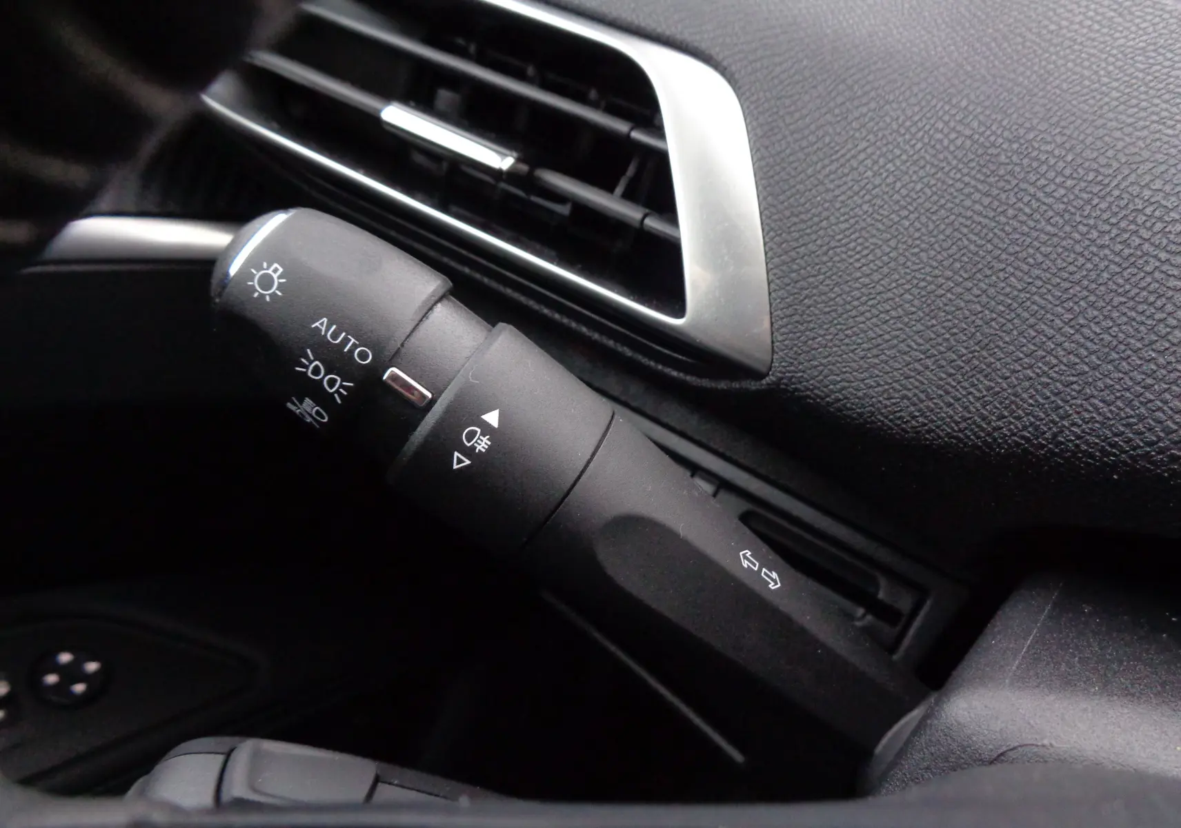 Gros plan sur la commande des feux et clignotants à gauche du tableau de bord noir du Peugeot 3008 gris Artense 2023.