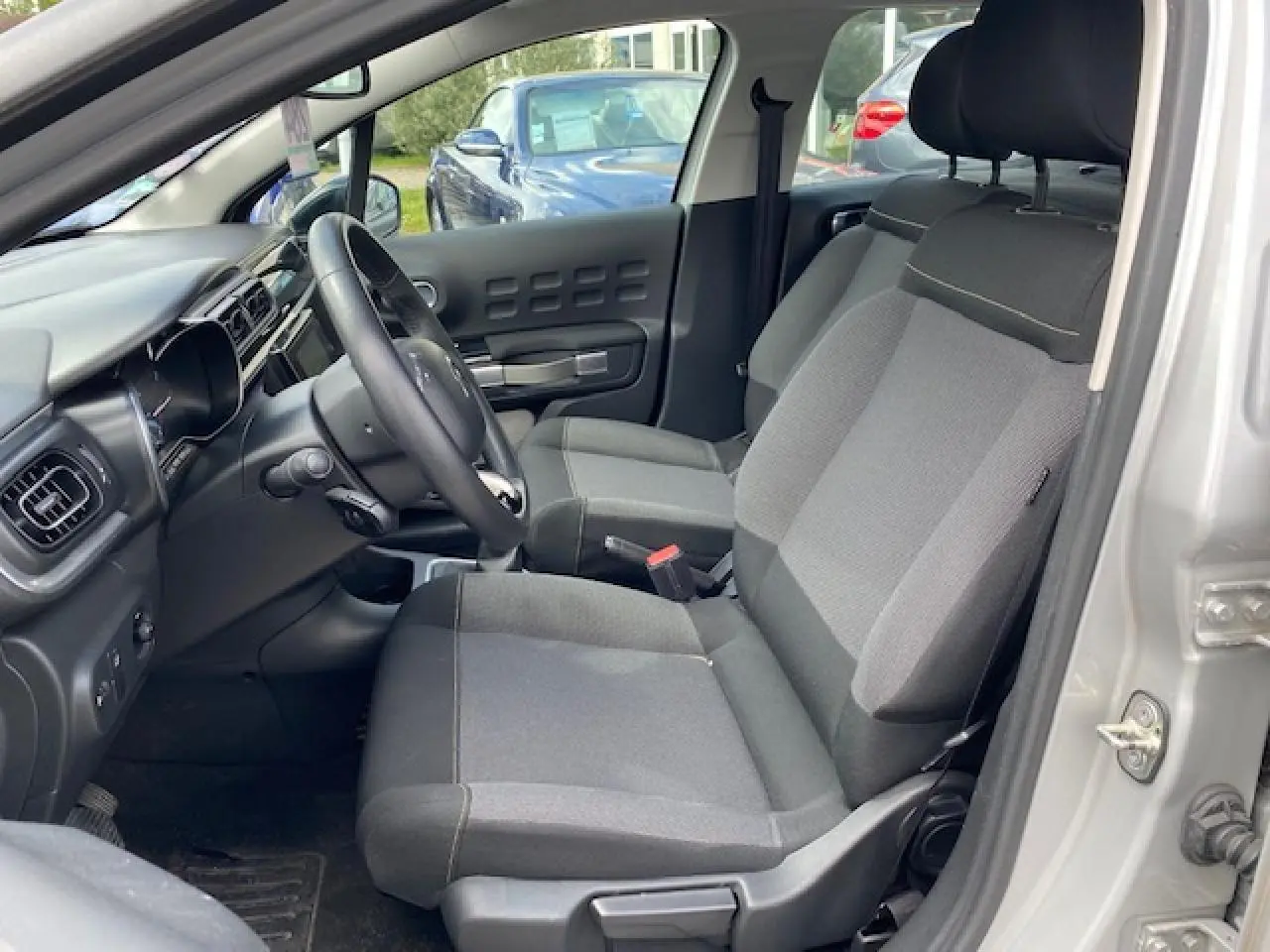 Vue intérieure côté conducteur de la Citroën C3 gris clair 2017 avec sièges en tissu Mica Grey et tableau de bord moderne.