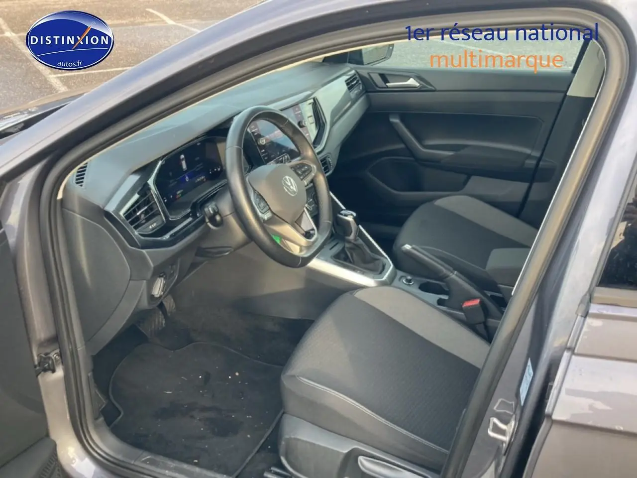 Vue intérieure côté conducteur de la Volkswagen Polo gris cendre 2025, avec tableau de bord digital et sièges tissu noir.