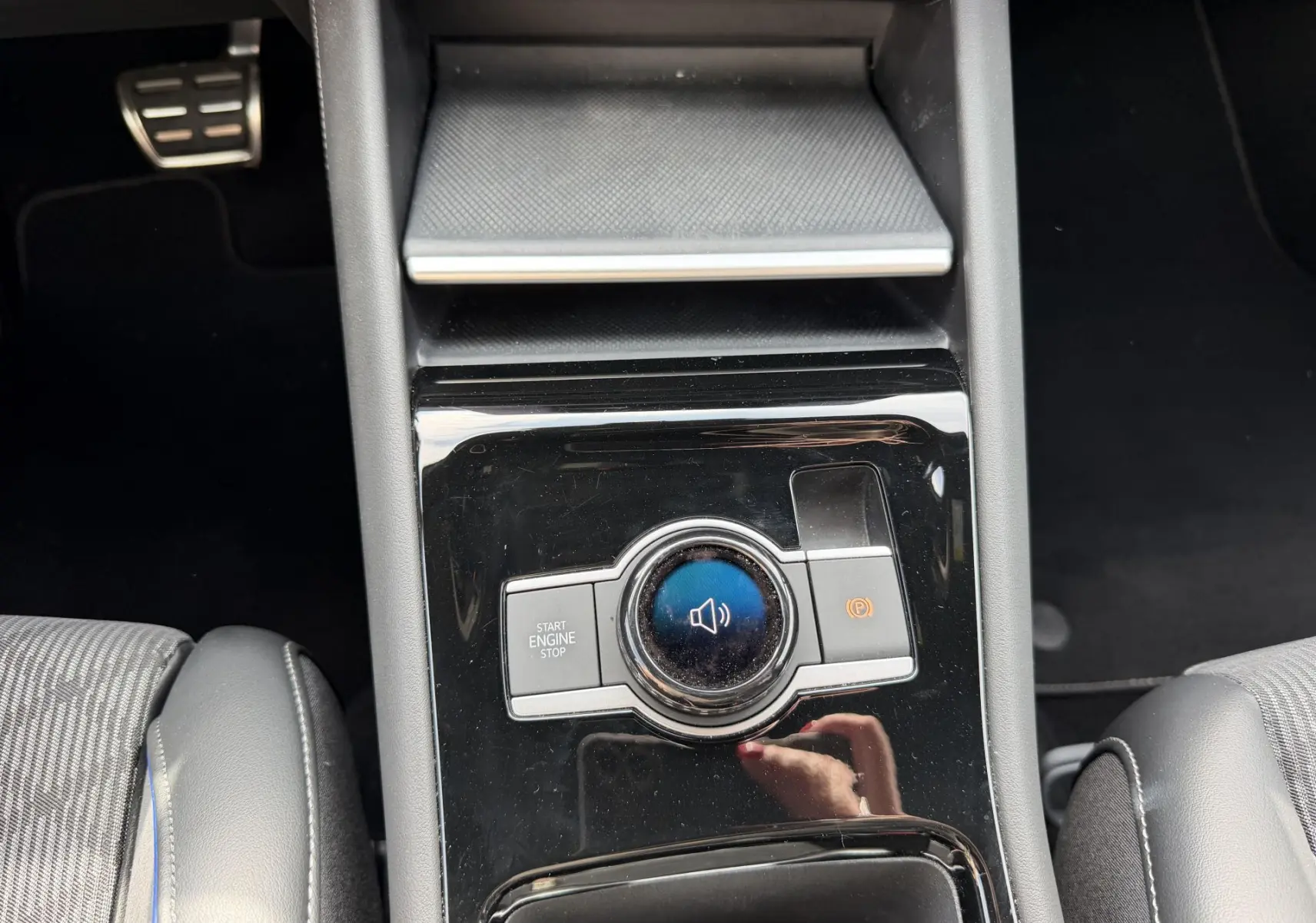 Vue plongeante sur la console centrale noire du Volkswagen Tiguan 2025 avec bouton Start/Stop et frein à main électronique.