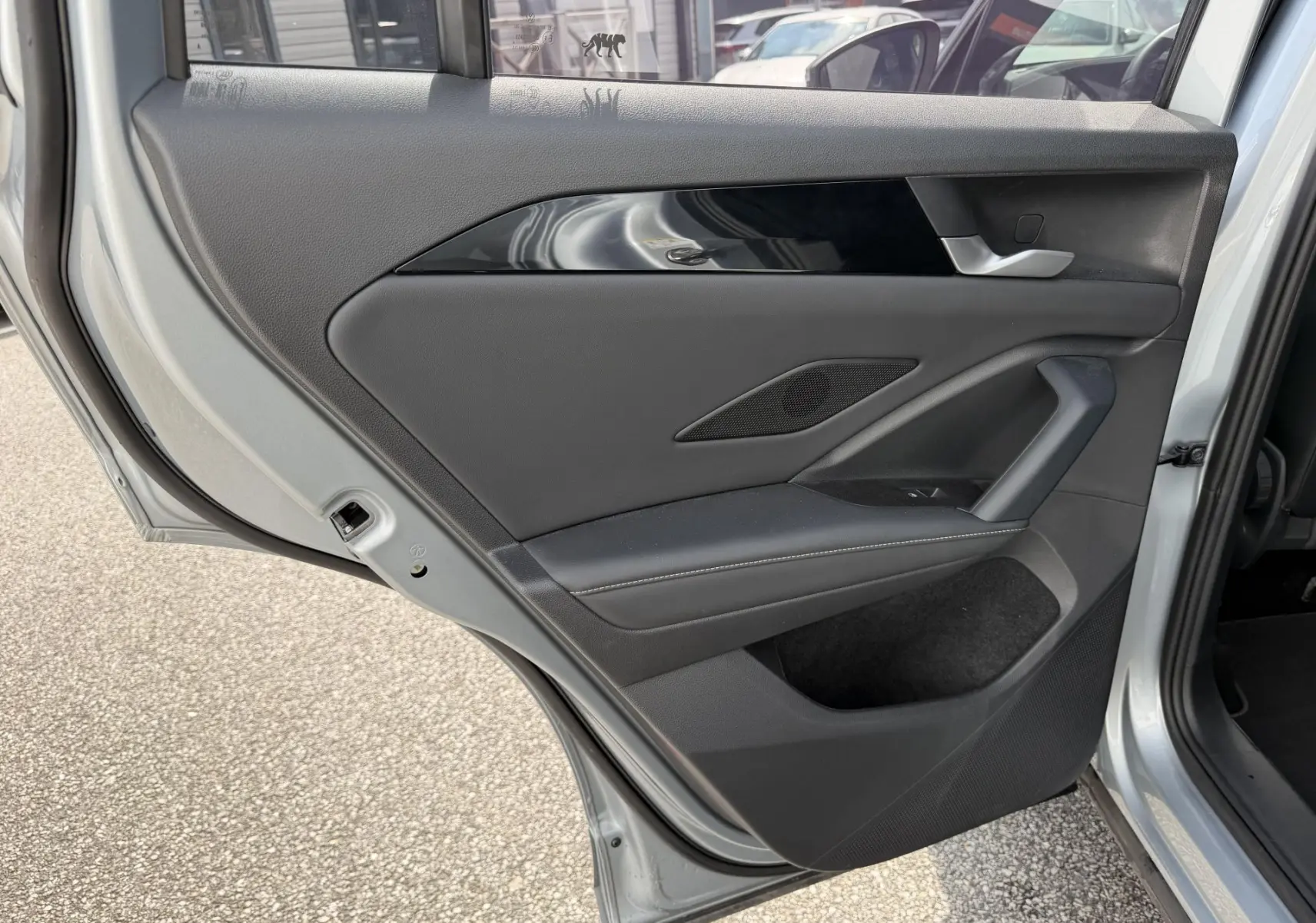 Vue rapprochée de la porte arrière gauche grise du Volkswagen Tiguan 2025, avec garniture noire et poignée argentée.