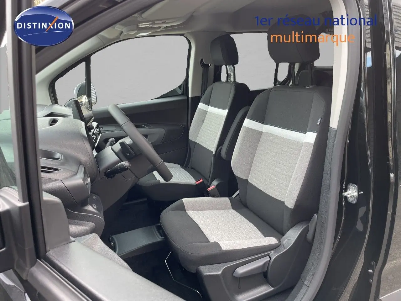 Vue intérieure côté conducteur du Citroën Berlingo noir Perla Nera, mettant en valeur les sièges tissu bicolores gris et noir.