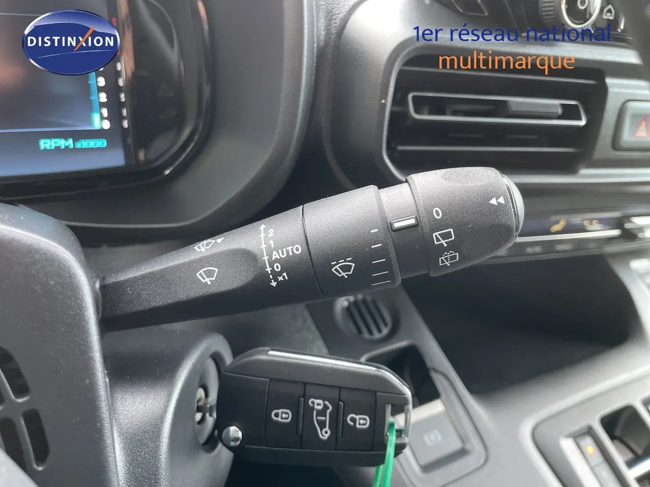 Gros plan sur la commande d’essuie-glace et la clé insérée dans le contacteur d’un Citroën Berlingo noir, intérieur côté gauche.