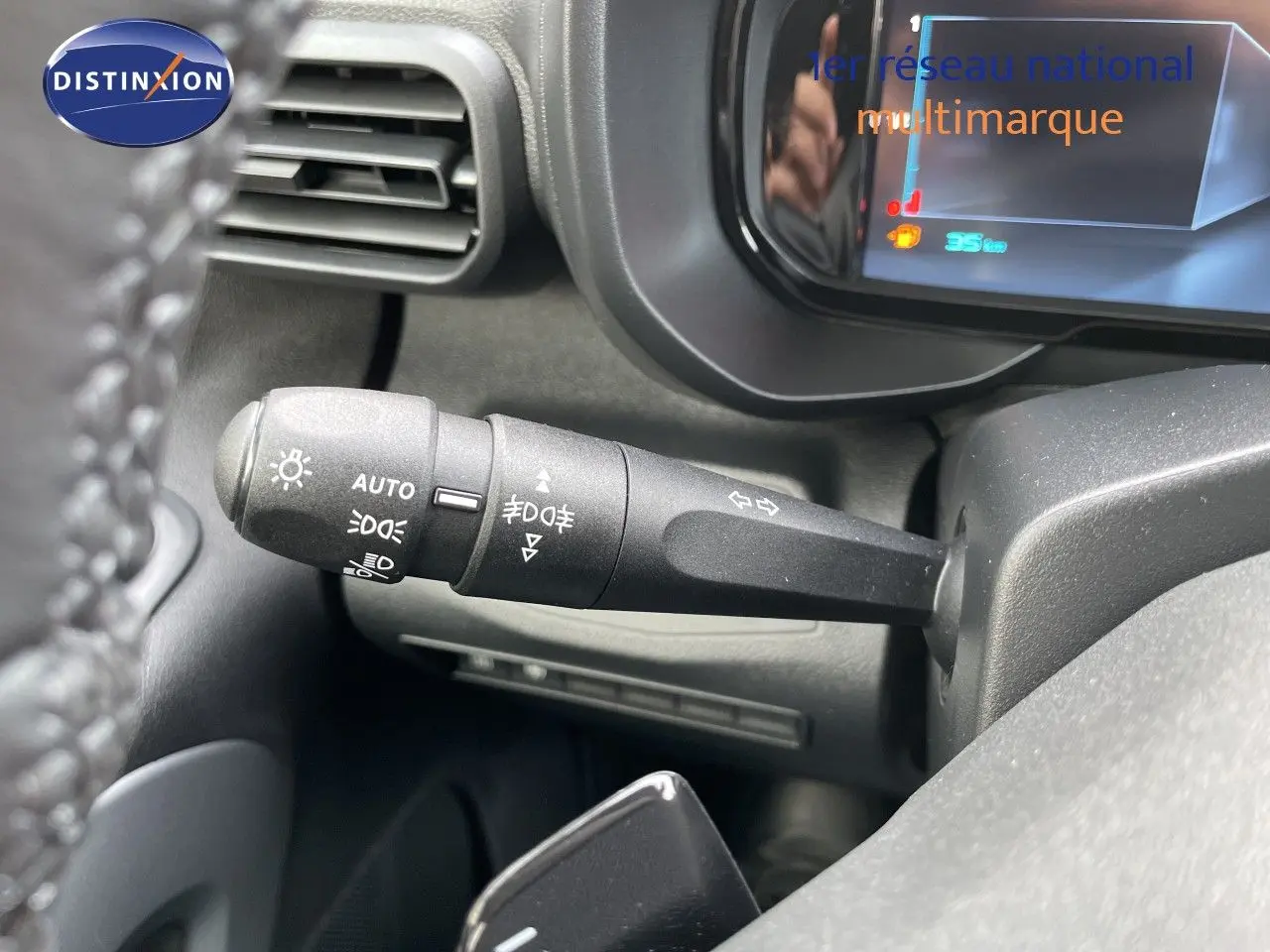 Gros plan sur la commande des feux et clignotants à gauche du volant dans le tableau de bord noir du Citroën Berlingo noir Perla Nera.