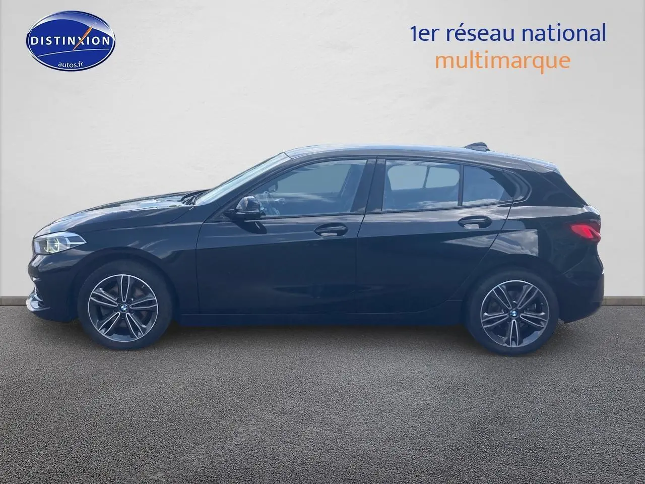 Profil latéral droit d'une BMW Série 1 noire 2023 avec jantes alliage et lignes sportives marquées.