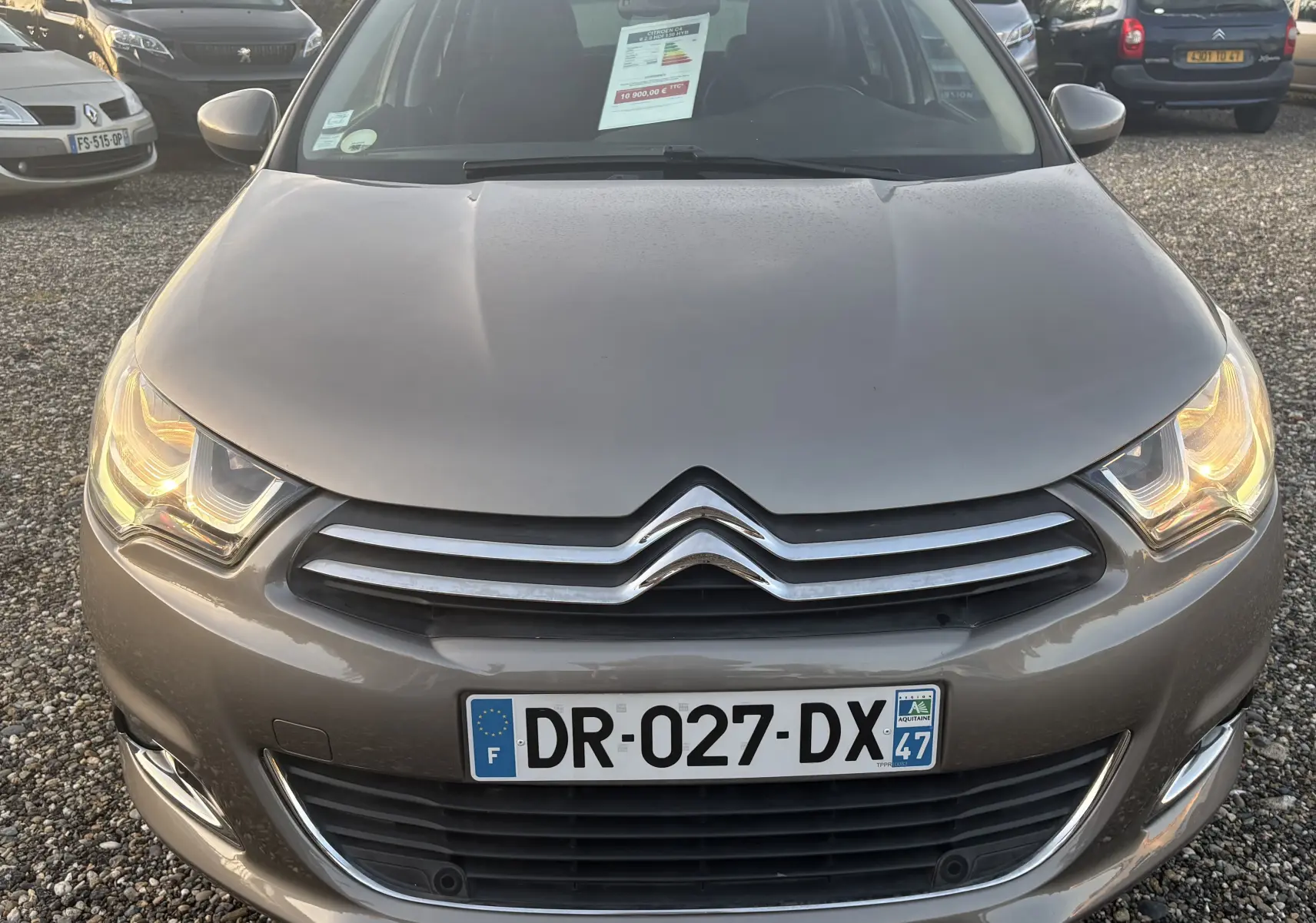 Vue frontale d'une Citroën C4 II gris métallisé avec phares allumés et plaque d'immatriculation française visible.