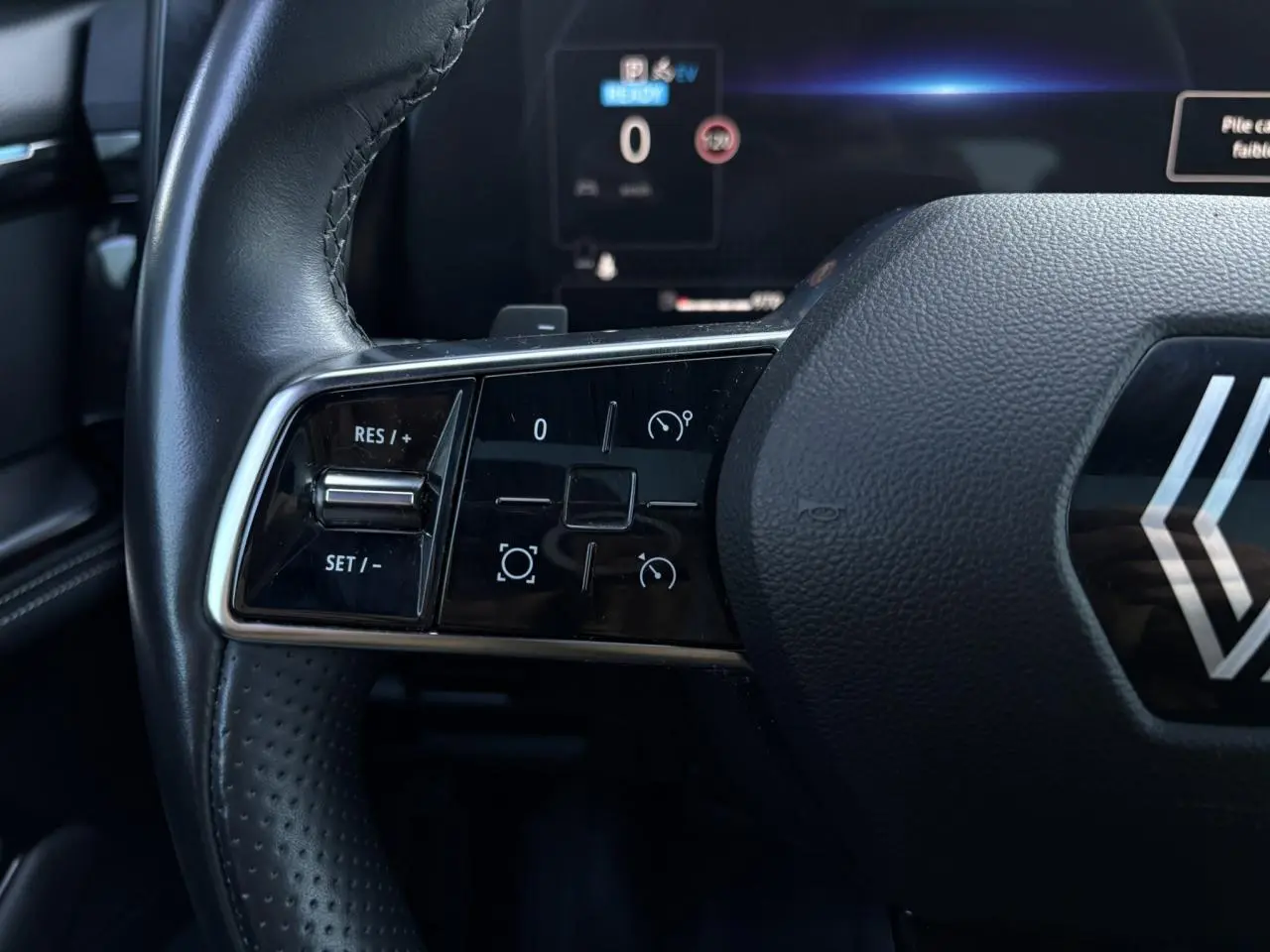 Gros plan sur les commandes à gauche du volant cuir du Renault Austral E-Tech 2024, affichage numérique en arrière-plan.