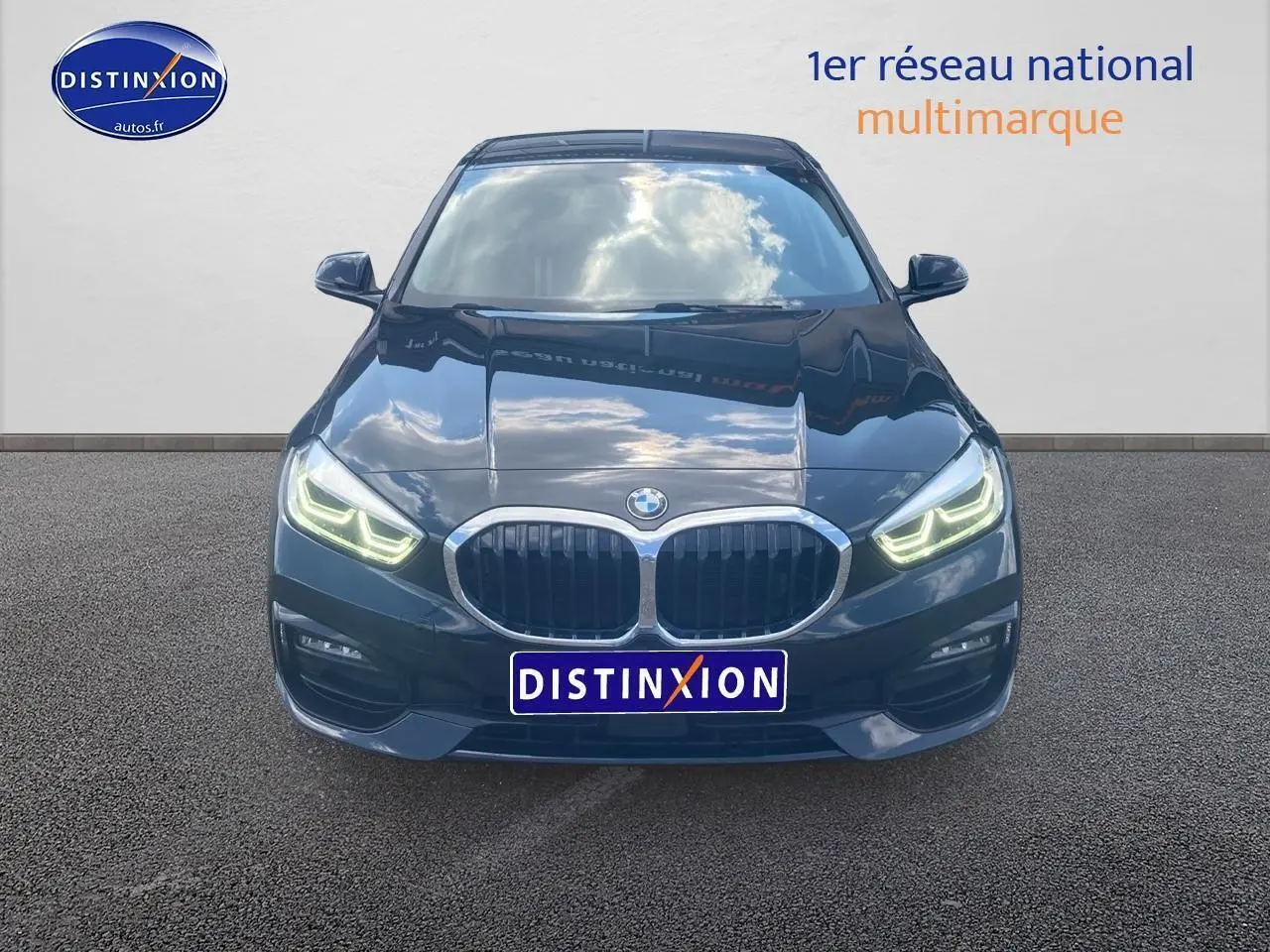 Vue frontale d'une BMW Série 1 noire avec phares LED allumés et calandre double haricot chromée.