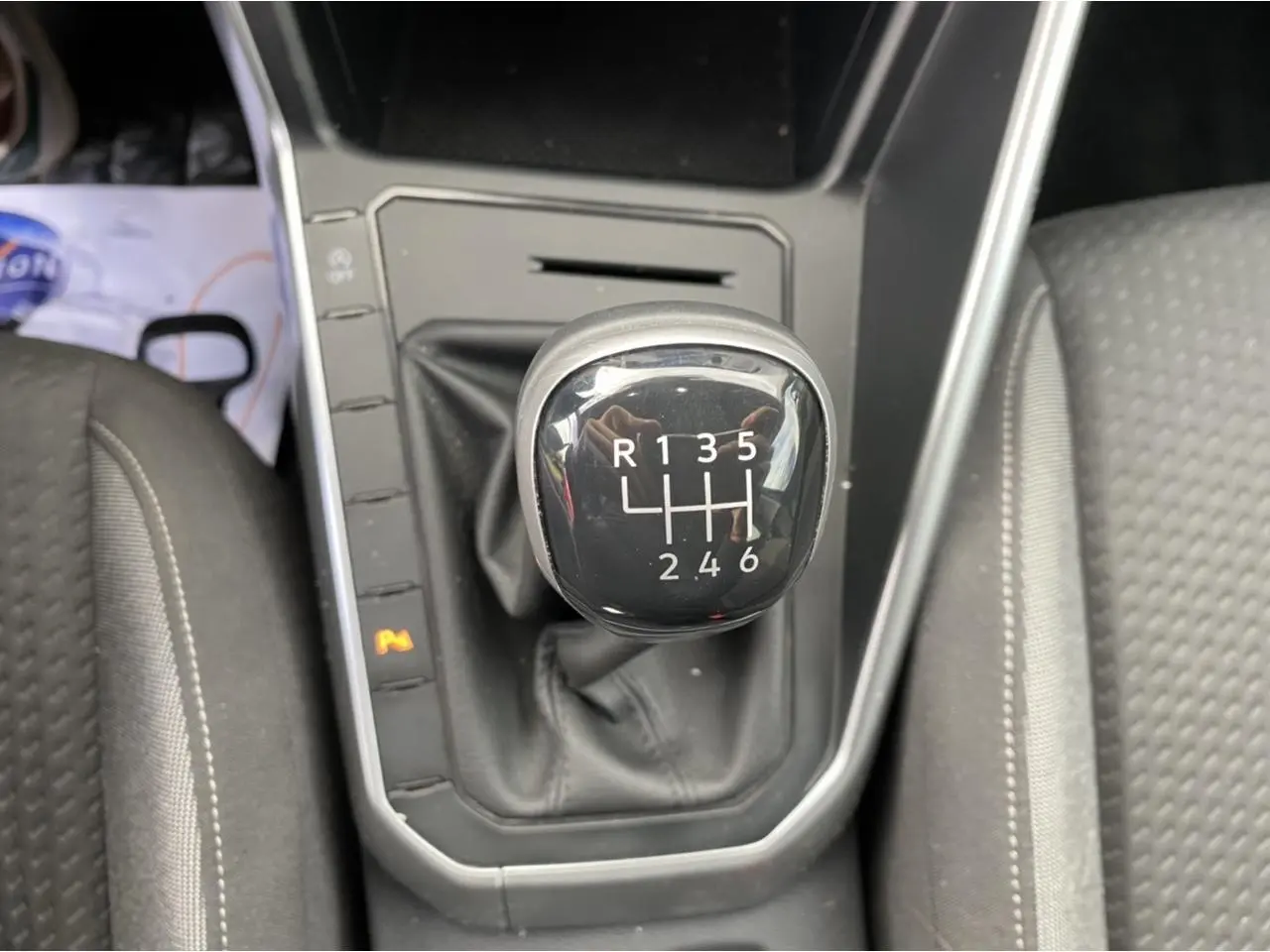 Gros plan sur le levier de vitesses manuel noir du Volkswagen Taigo 2022, entouré de sièges en tissu gris.