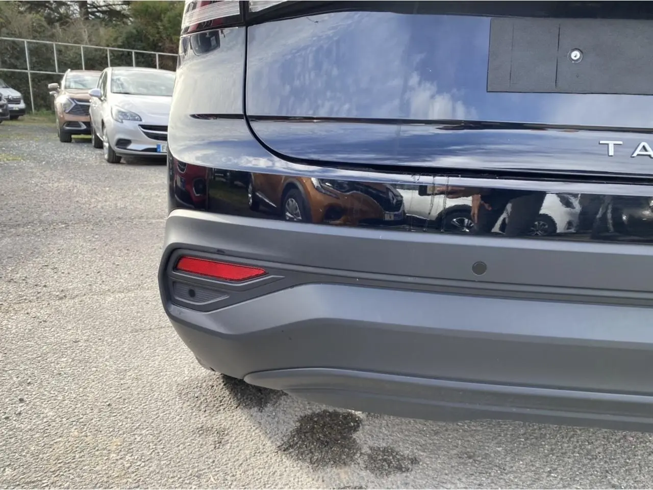 Gros plan sur le pare-chocs arrière noir intense du Volkswagen Taigo 2022 avec capteur de stationnement visible.