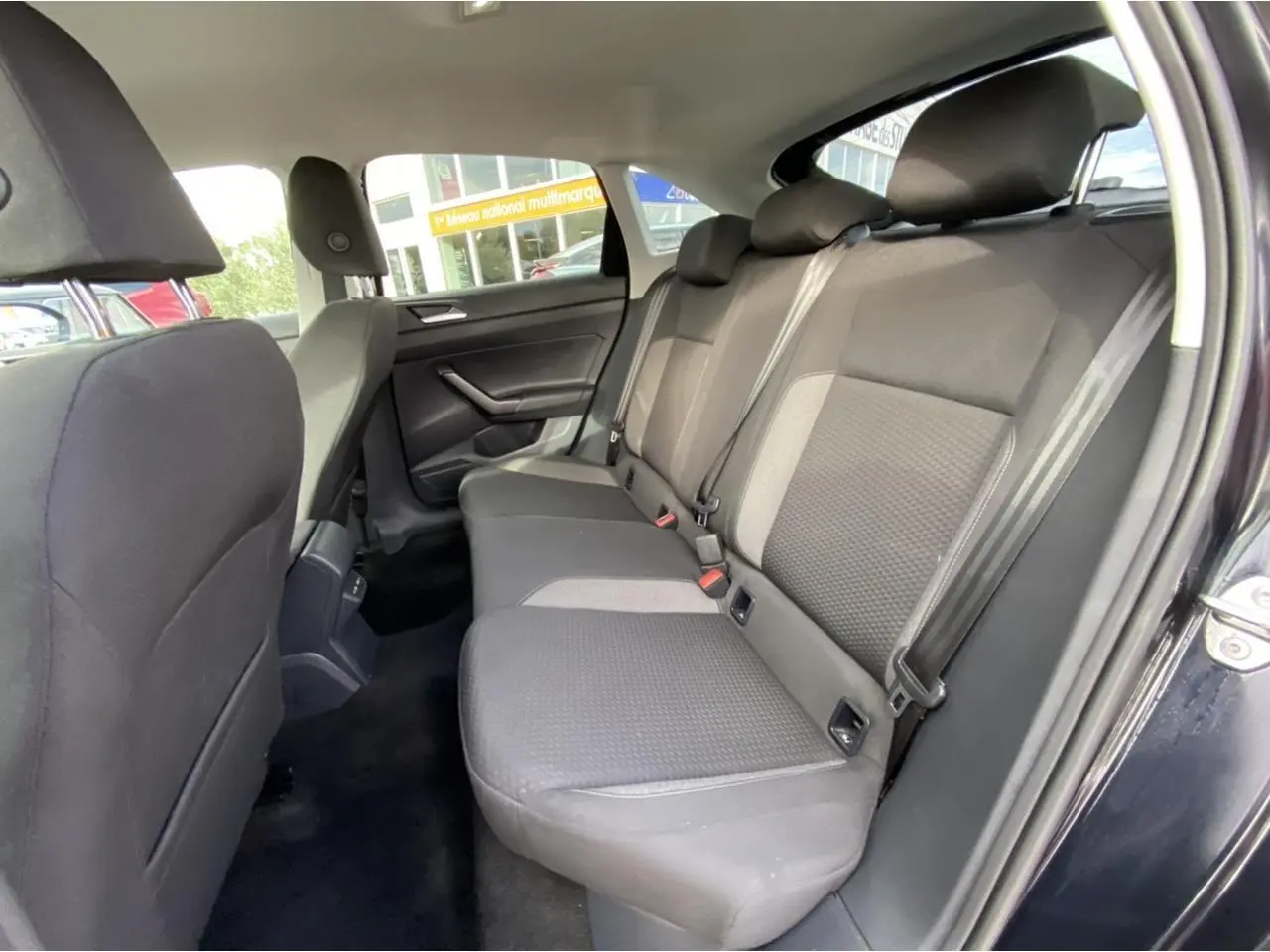 Vue intérieure côté droit des sièges arrière noirs du Volkswagen Taigo 2022 avec porte ouverte et ceinture de sécurité visible.