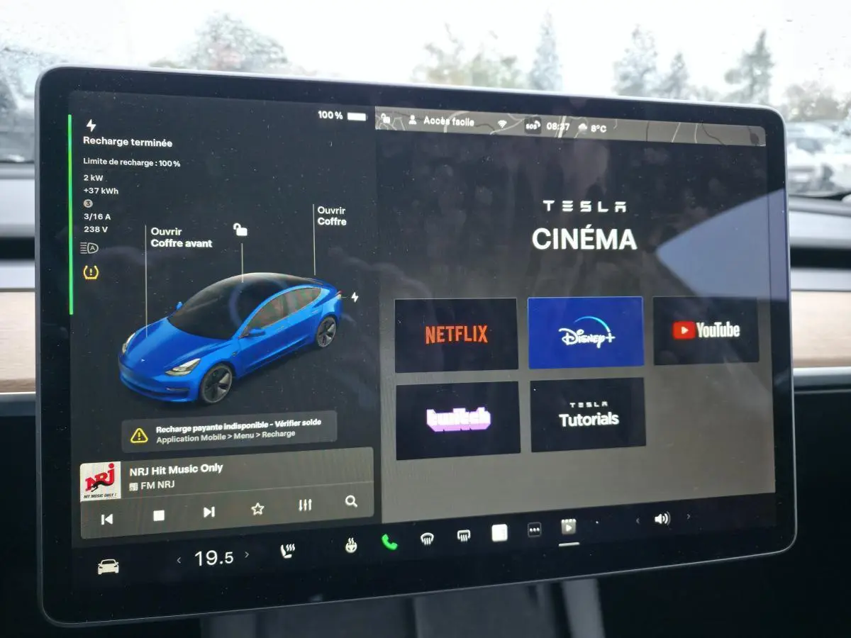 Écran tactile central affichant l'interface multimédia Tesla Cinema avec une illustration 3D d'une Model 3 bleu foncé.
