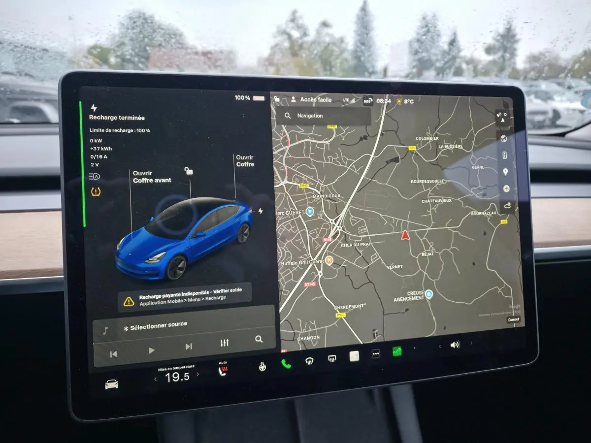 Écran tactile intérieur montrant la Tesla Model 3 RWD bleu foncé avec carte de navigation et statut de recharge.