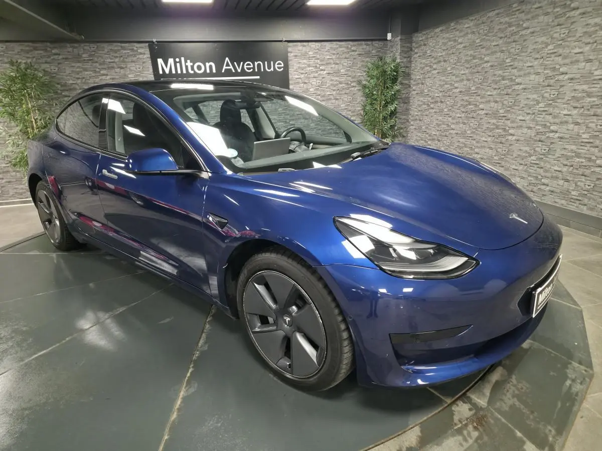 Tesla Model 3 RWD bleu foncé vue 3/4 avant droit, avec jantes 18 pouces et poignées couleur carrosserie.