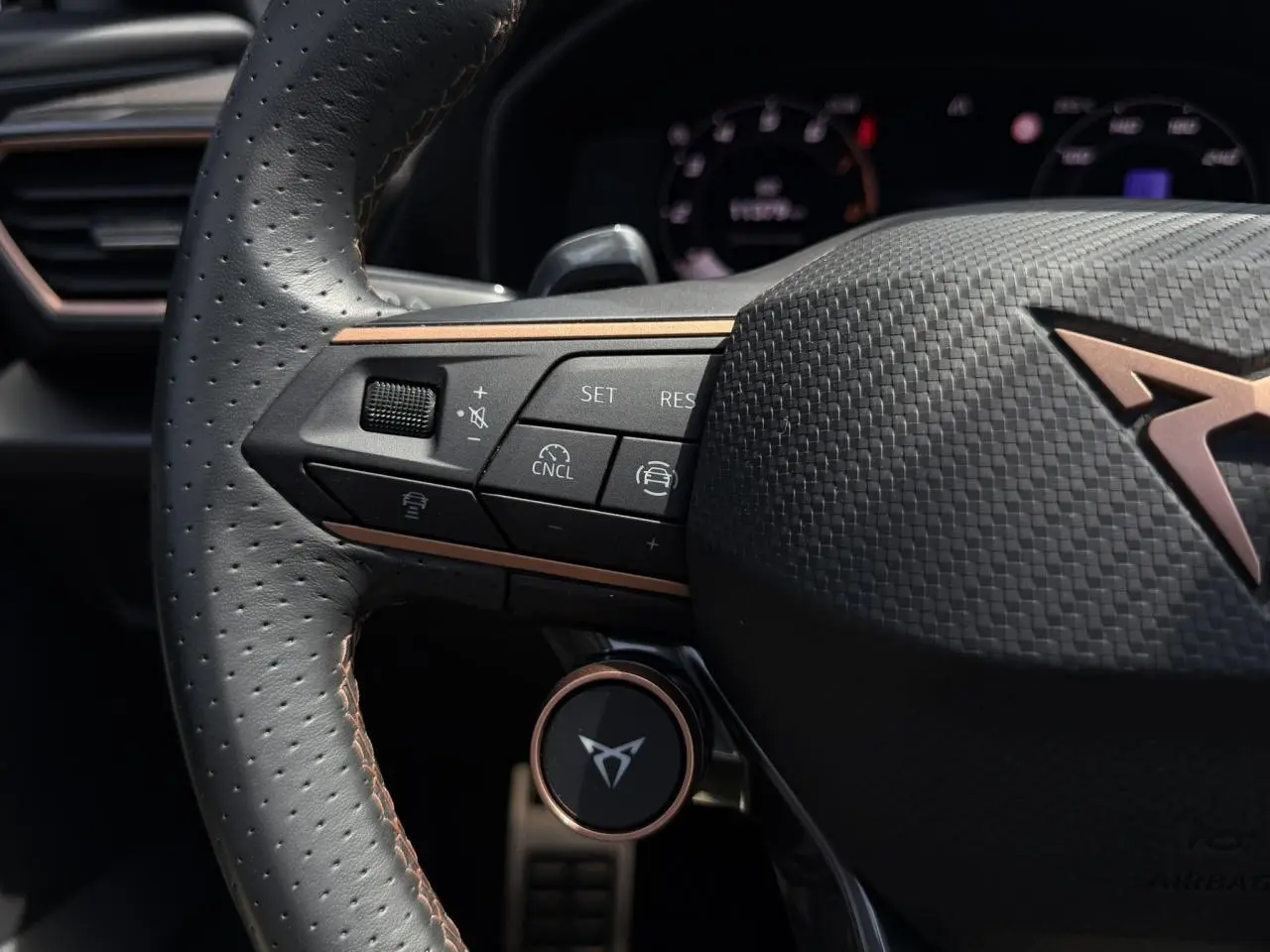 Gros plan sur le volant cuir perforé noir avec logo CUPRA cuivré et commandes multifonctions du Formentor 2025.