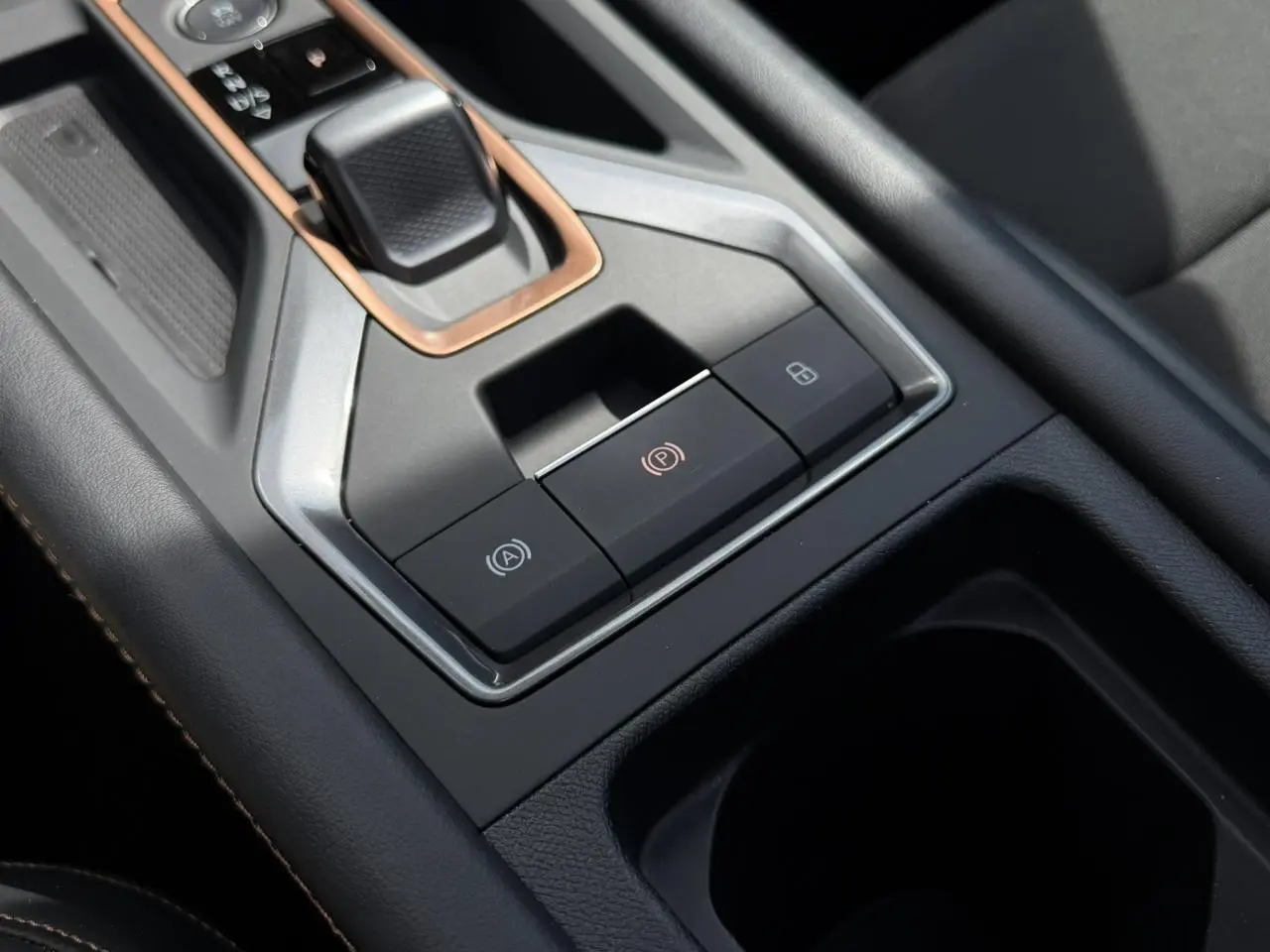 Gros plan sur la console centrale noire du CUPRA Formentor blanc, avec commandes électroniques et insert cuivré autour du levier.
