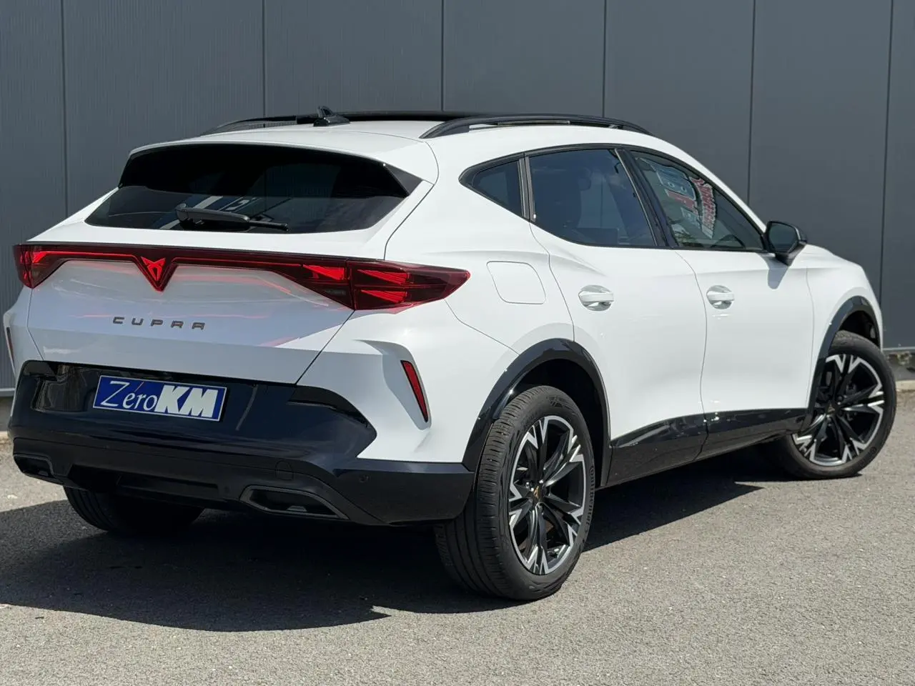 Vue 3/4 arrière droite d’un CUPRA Formentor blanc Neige avec jantes alliage noires et signature lumineuse Tri-LED.