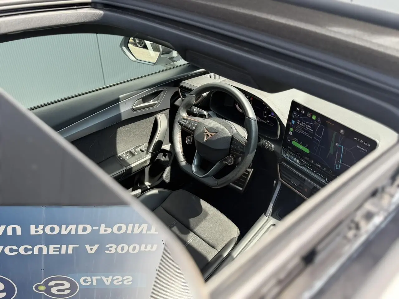 Vue intérieure par le toit ouvrant panoramique montrant le volant Supersports CUPRA et l’écran tactile HD du Formentor blanc.