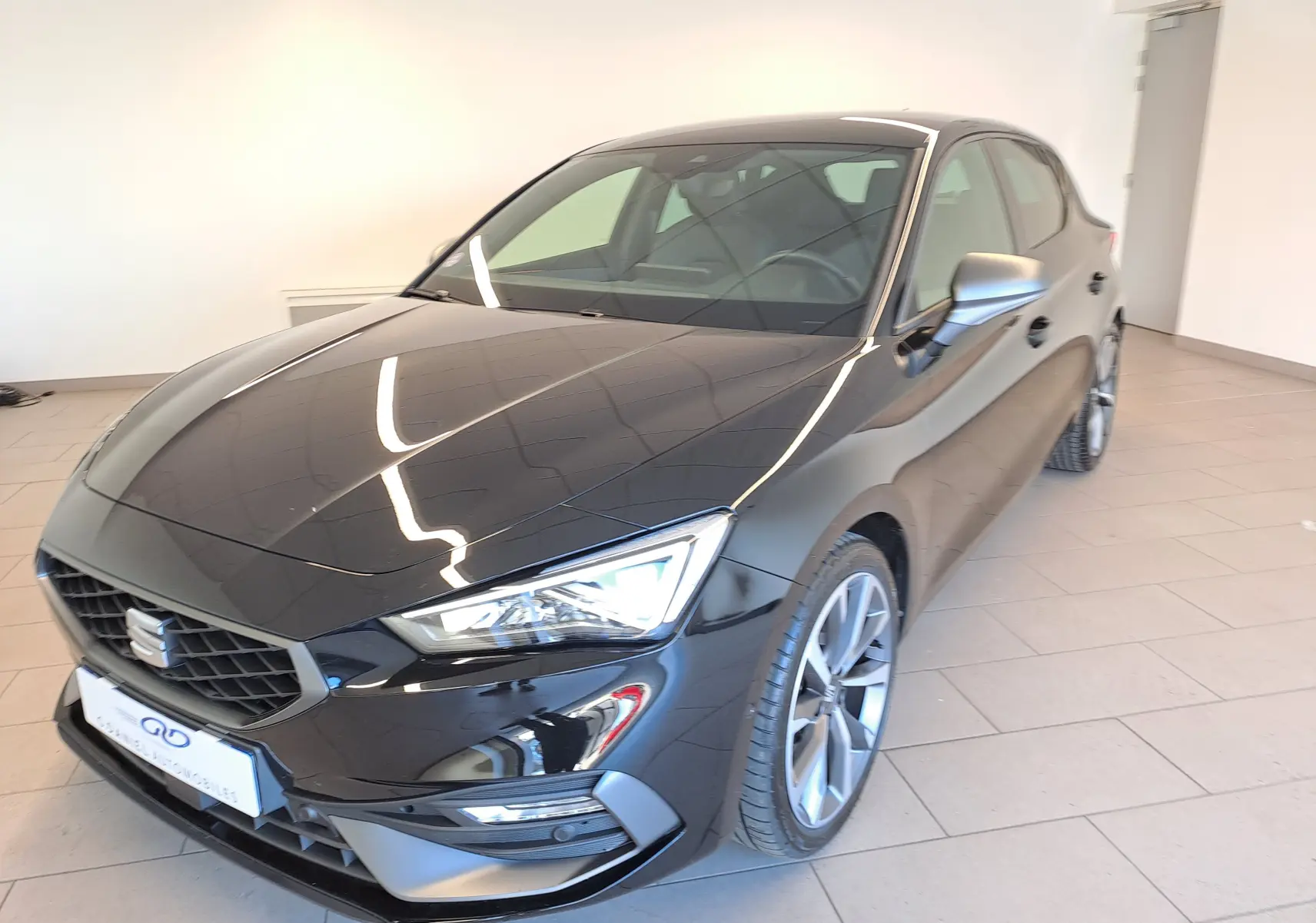 SEAT LEON 1.5 eTSI Hybrid 2024 en noir minuit, vue 3/4 avant droit avec jantes alliage et phares LED.